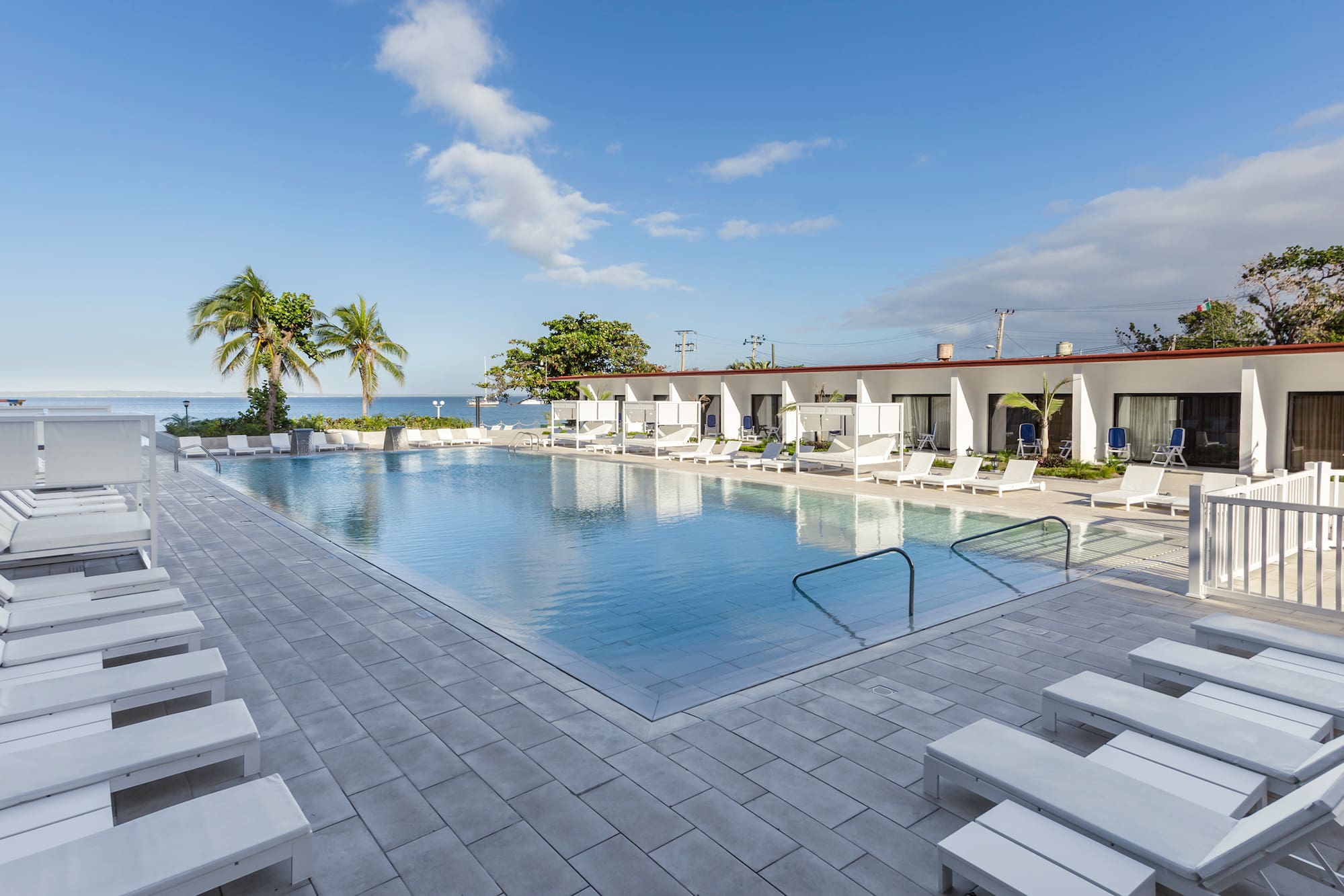 a pool with lounge chairs and a building with a body of water