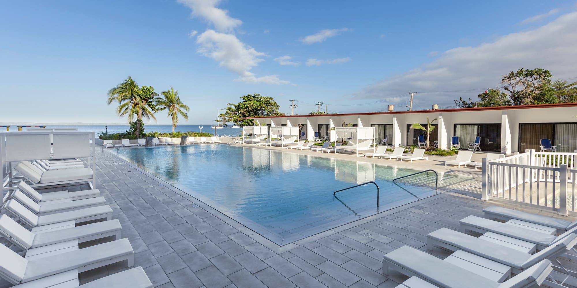 a pool with lounge chairs and a building with a body of water