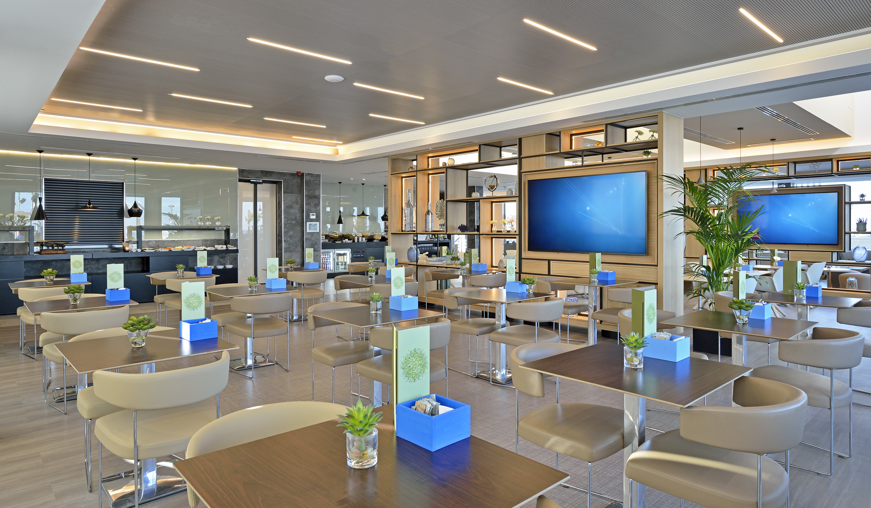 Spacious, brightly lit modern restaurant with a buffet and multiple TV displays.