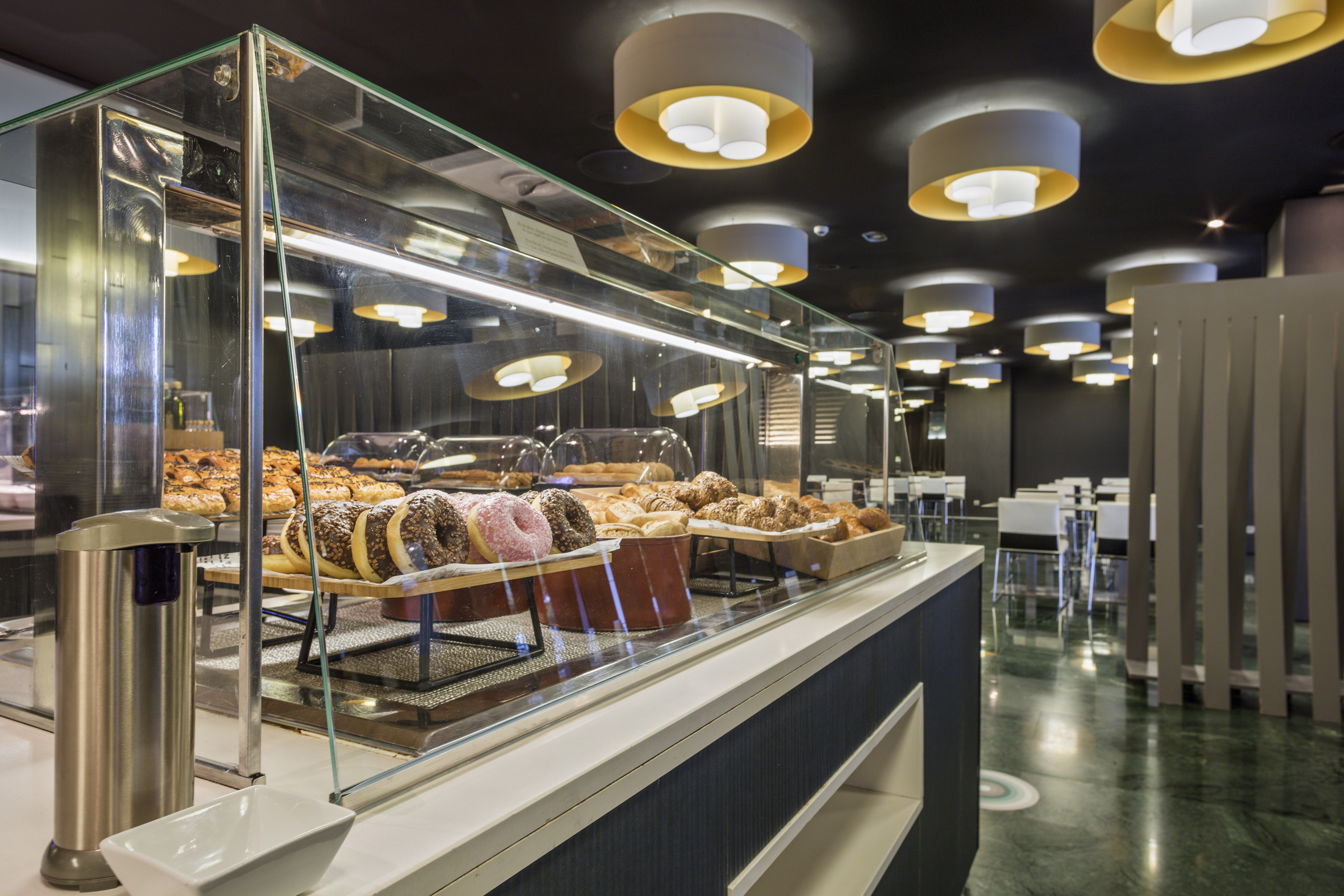 Modern breakfast buffet with donuts, croissants, and baked pastries.