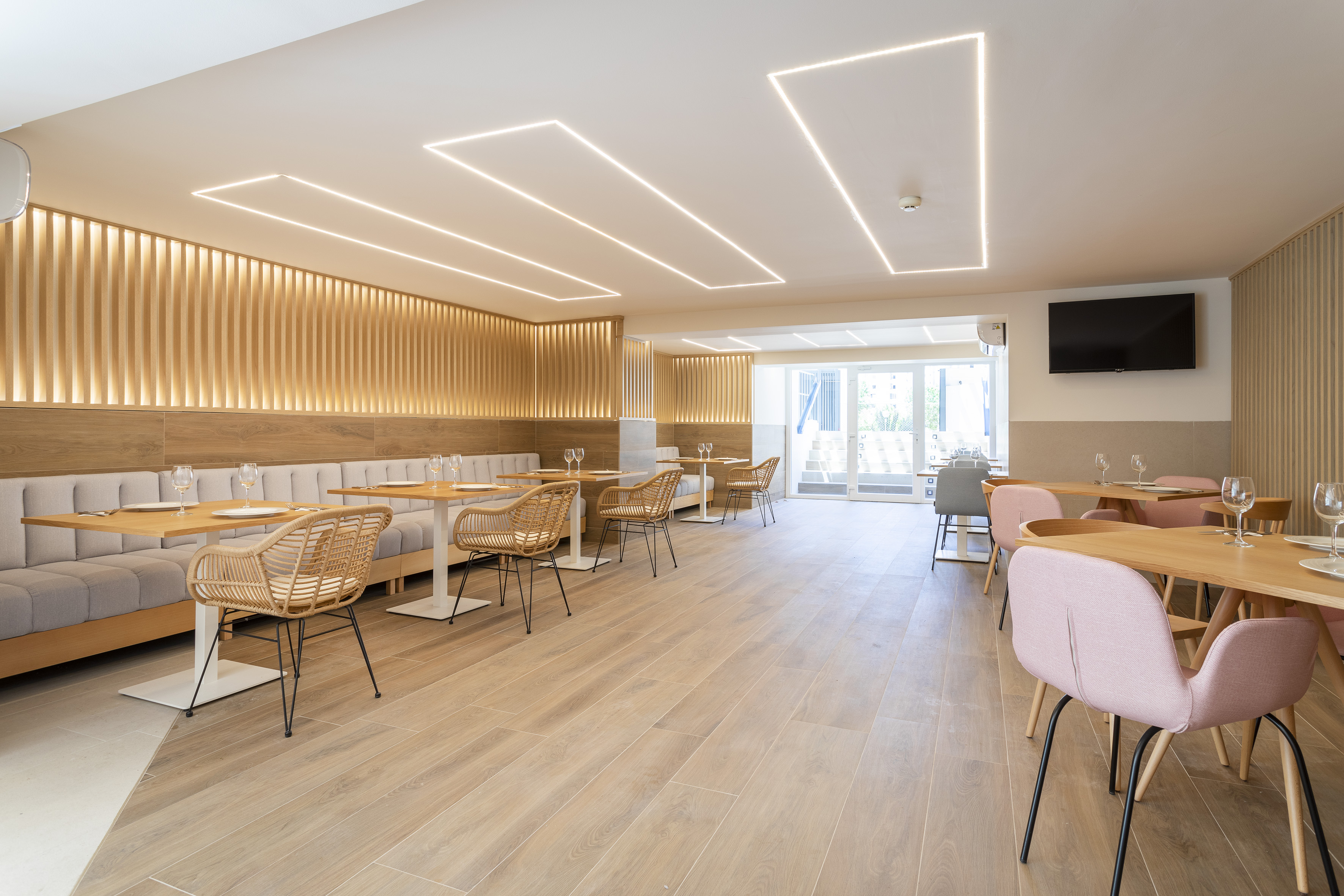 Modern restaurant dining, wood walls, banquettes, and linear ceiling lights.