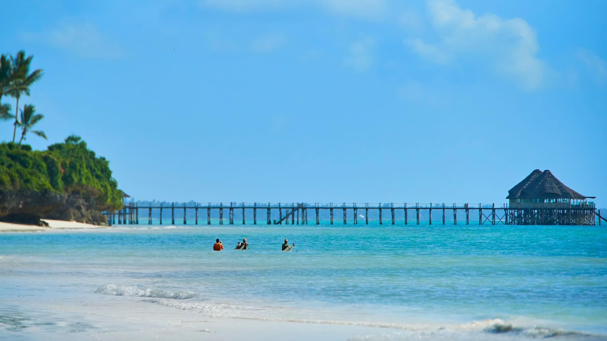 people on the beach with a pier