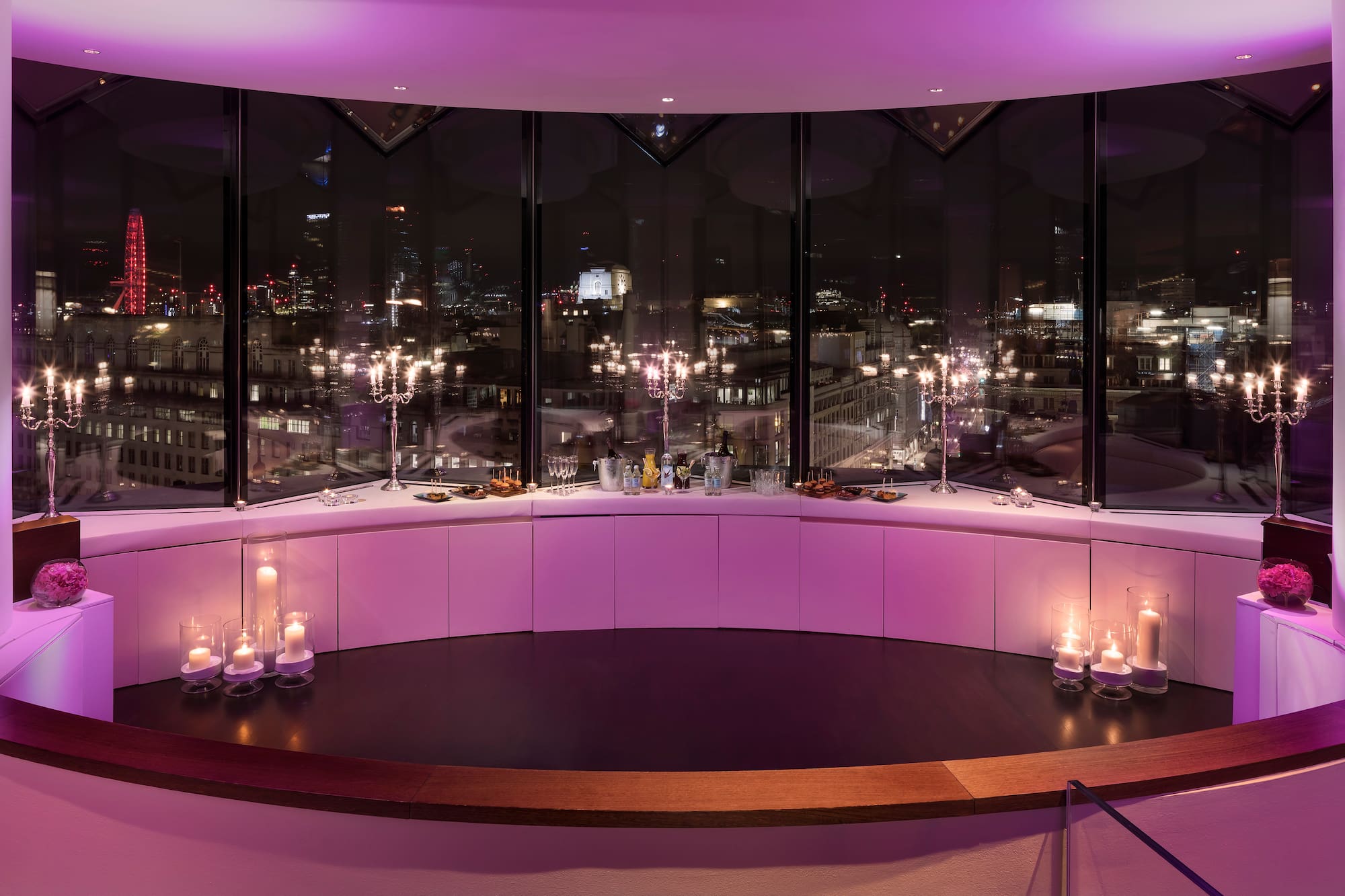 A room featuring a large window and a table adorned with candles.