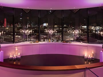 A room featuring a large window and a table adorned with candles.