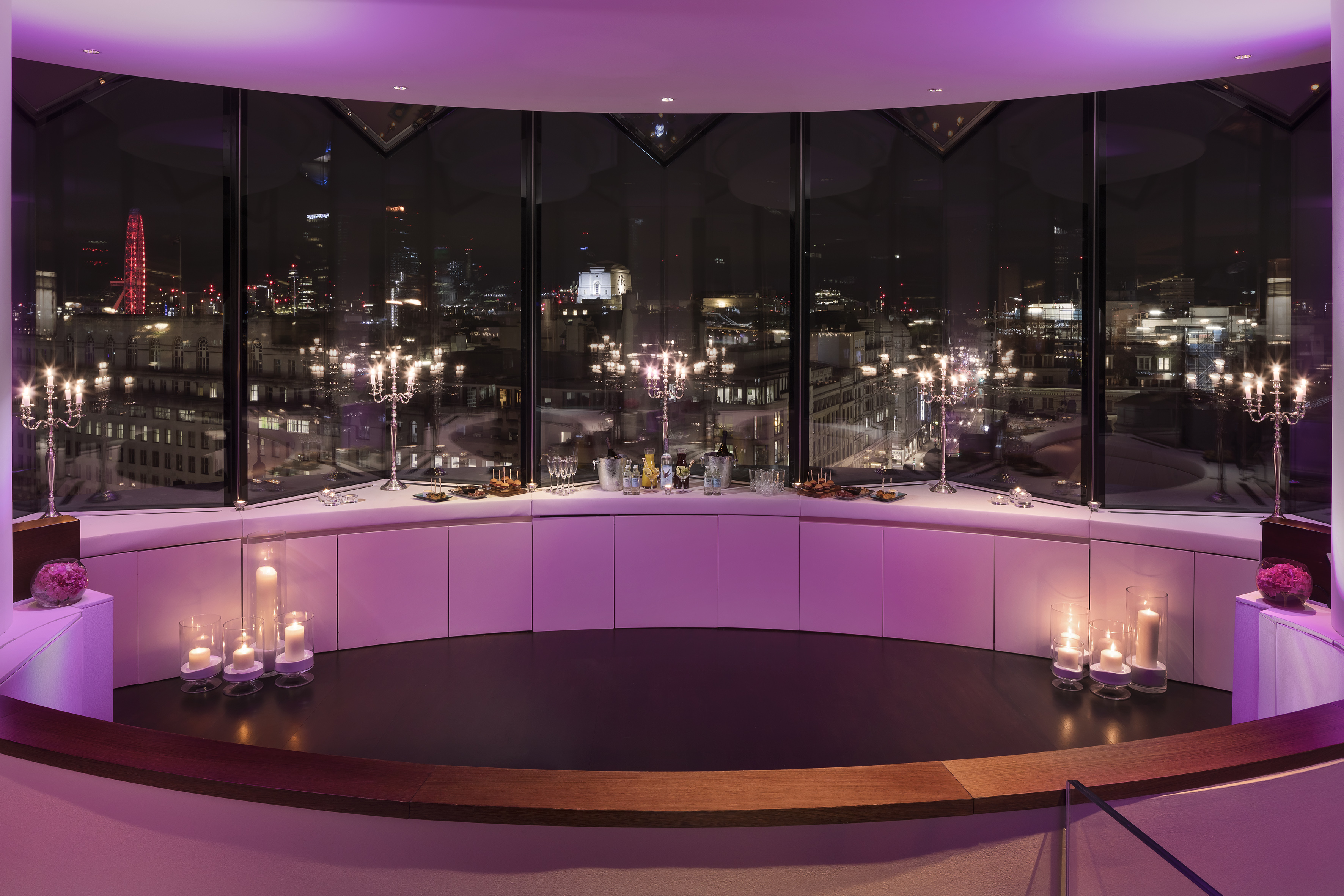 A room featuring a large window and a table adorned with candles.