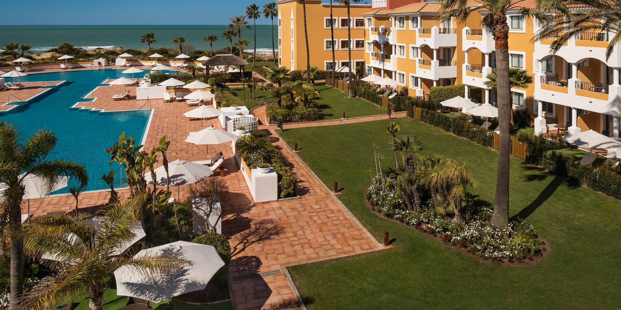 a pool and buildings with palm trees and umbrellas