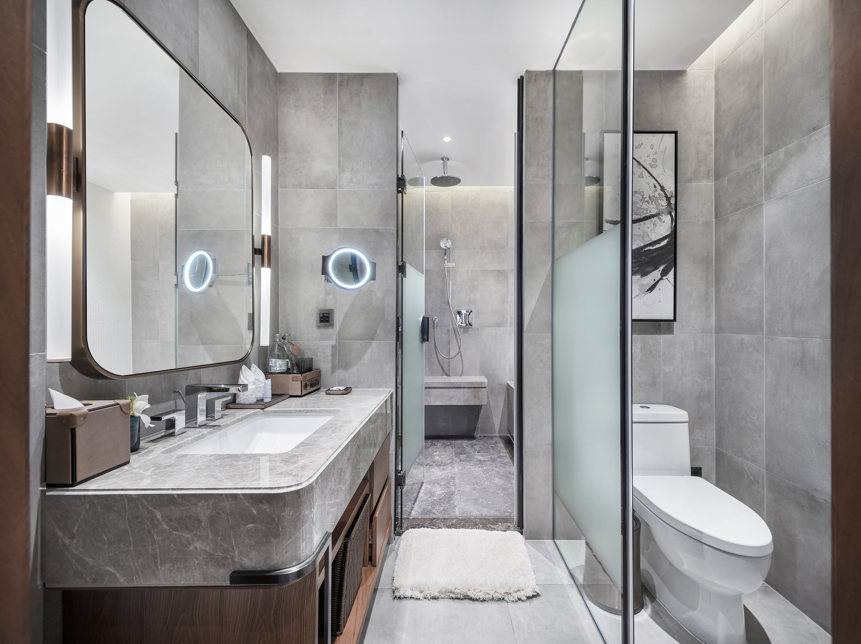 Modern grey bathroom with marble vanity, large mirror, and glass shower.