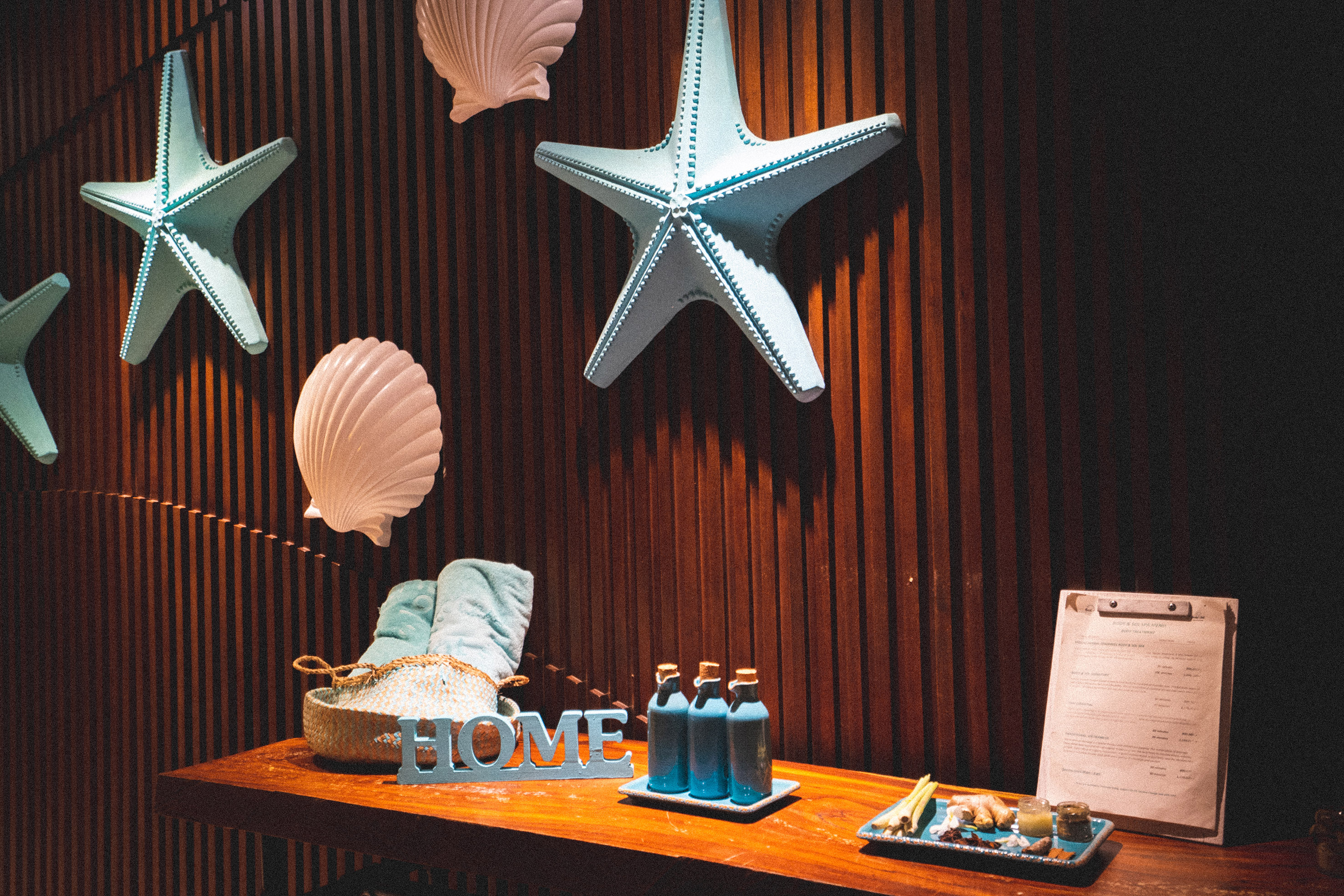 Spa decor with blue starfish, seashells, 'HOME' sign, and wellness amenities.