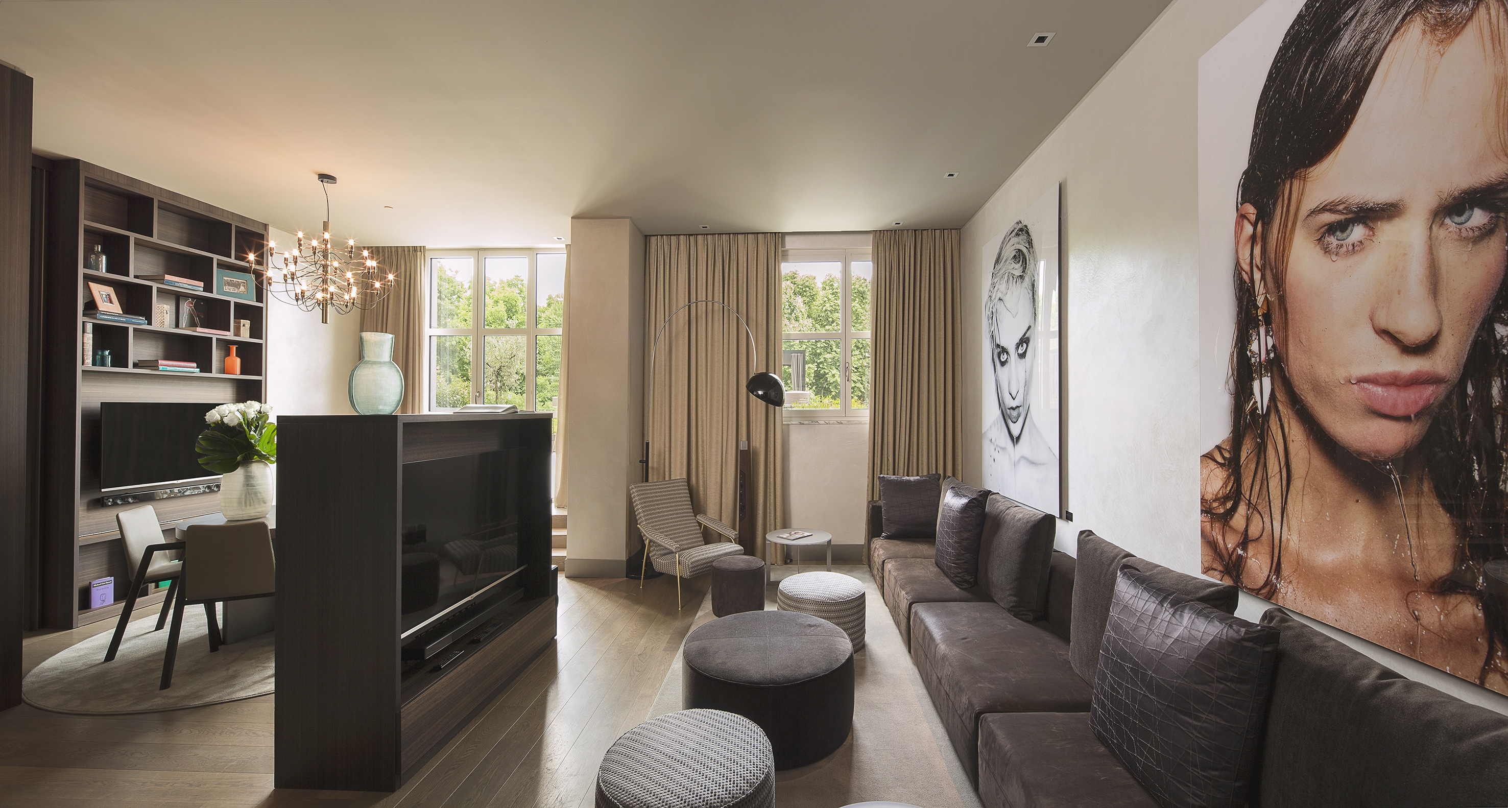 Sleek modern living room with brown sofa, large portrait art, and dining.