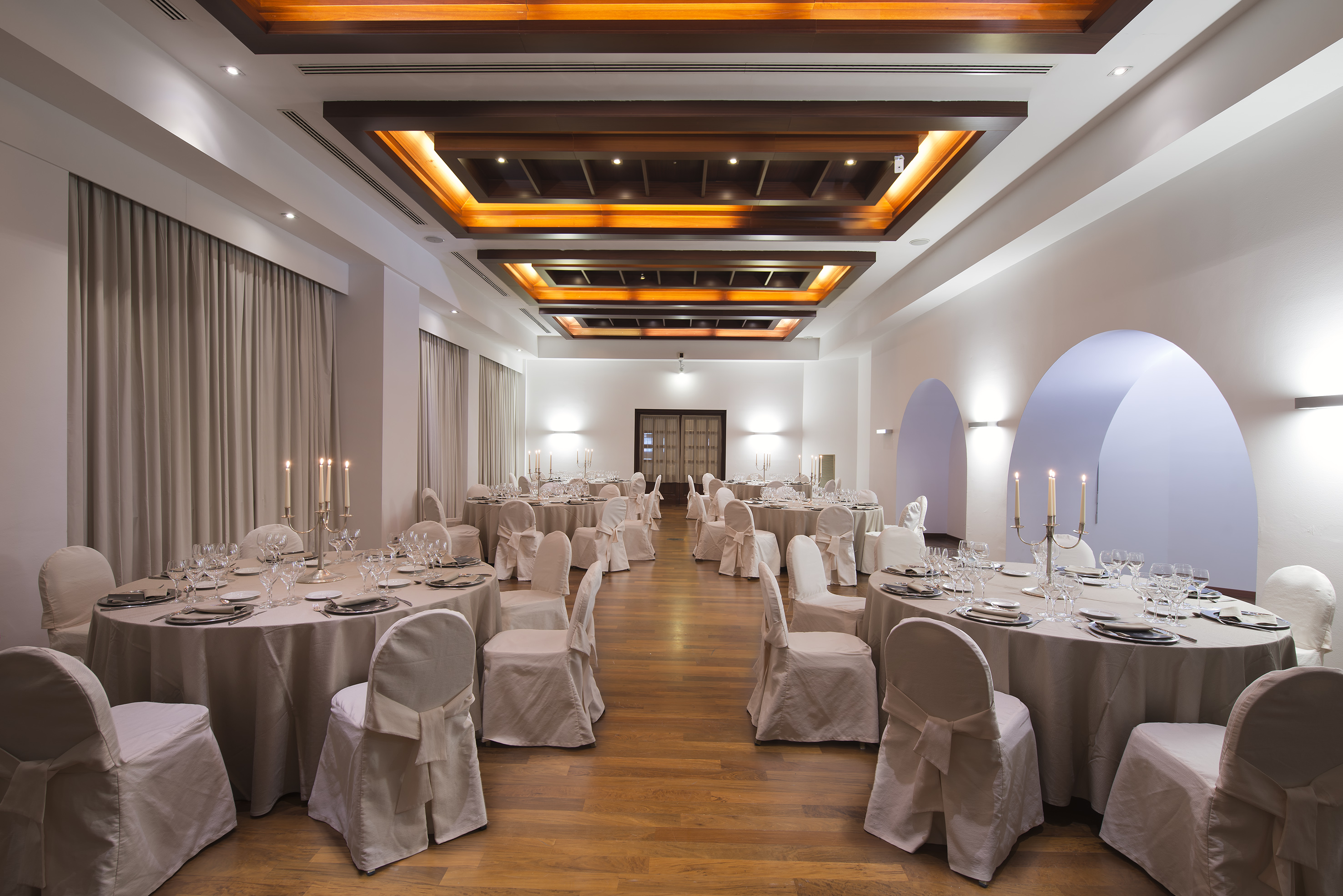 Elegant banquet hall with set dining tables and decorative ceiling.