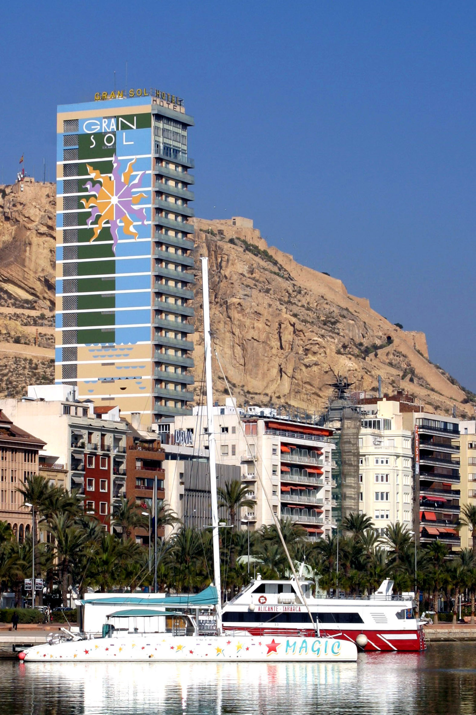 Gran Sol Hotel, Santa Bárbara Castle, and catamaran in Alicante port.