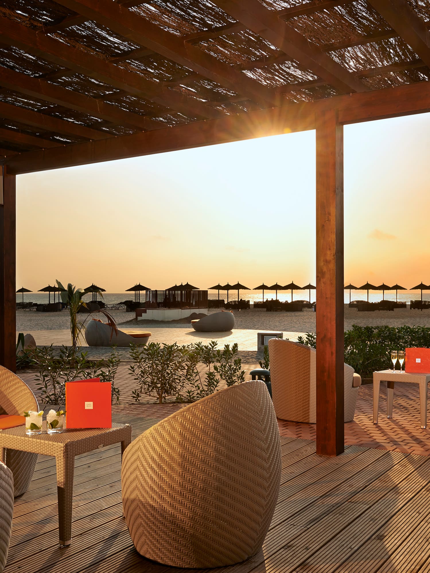 a patio with chairs and tables on a beach