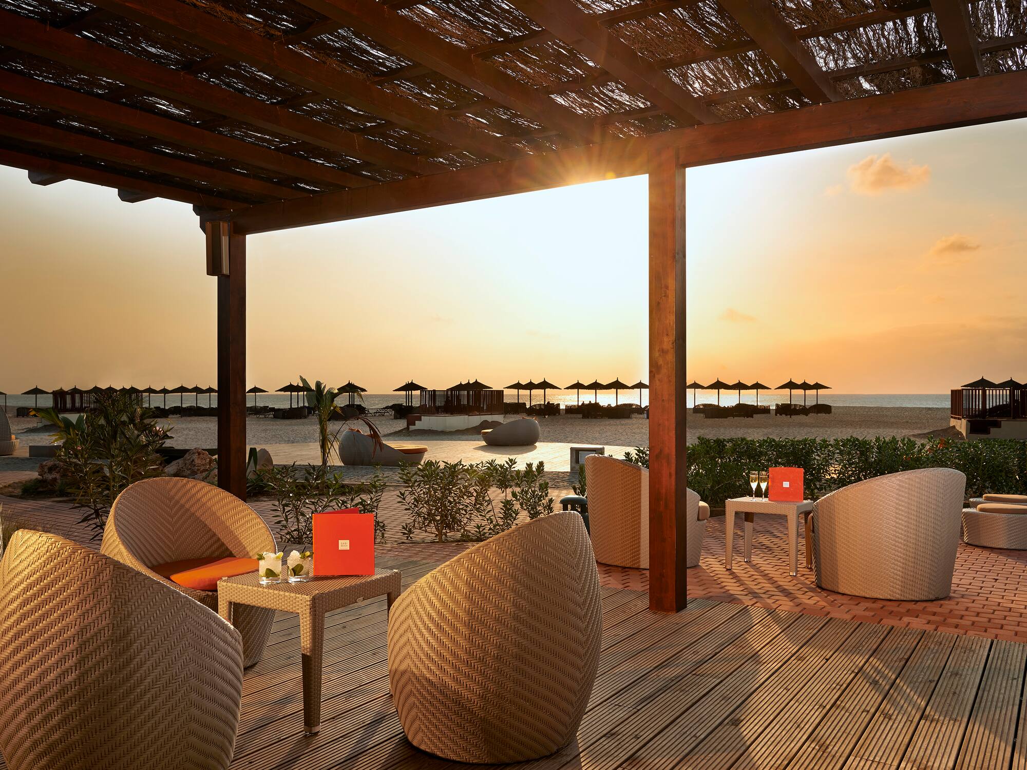 a patio with chairs and tables on a beach