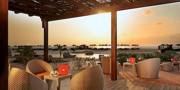 a patio with chairs and tables on a beach