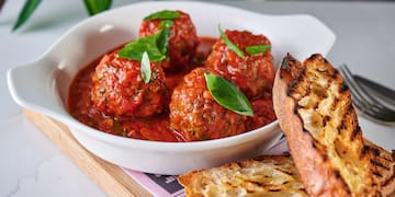 a bowl of meatballs and a piece of bread