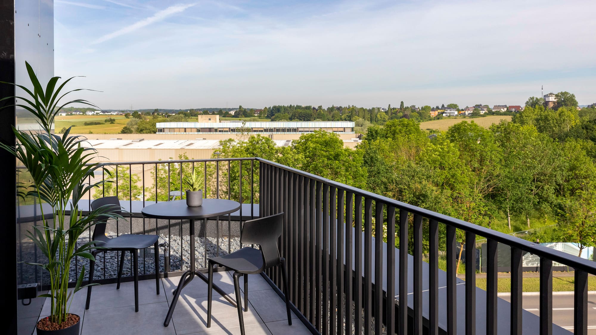 a table and chairs on a balcony overlooking trees and buildings
