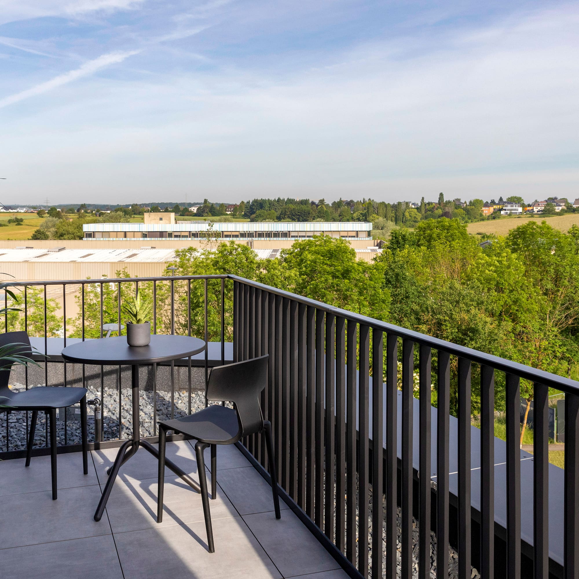 a table and chairs on a balcony overlooking trees and buildings