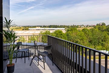 a table and chairs on a balcony overlooking trees and buildings
