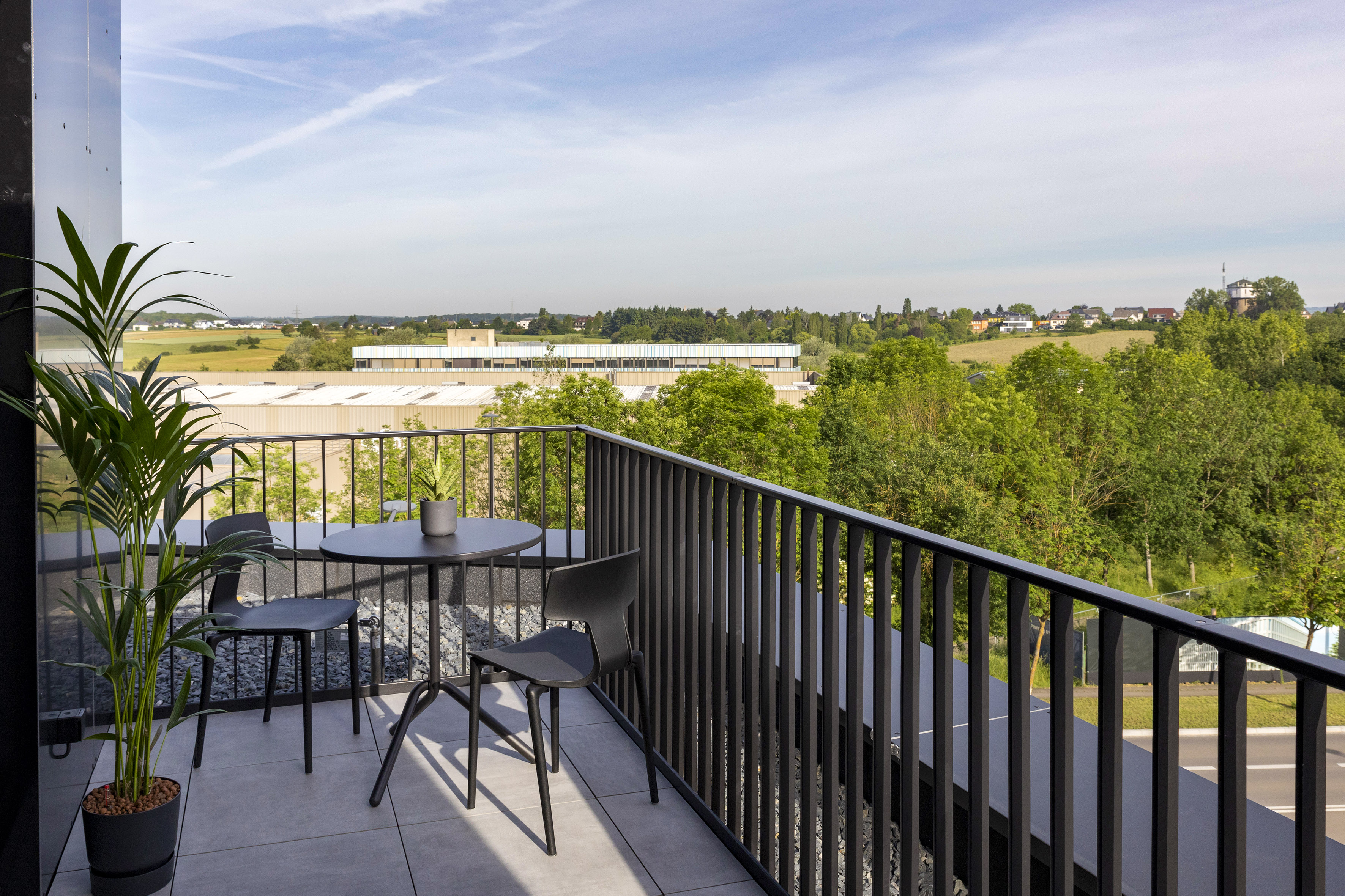 a table and chairs on a balcony overlooking trees and buildings