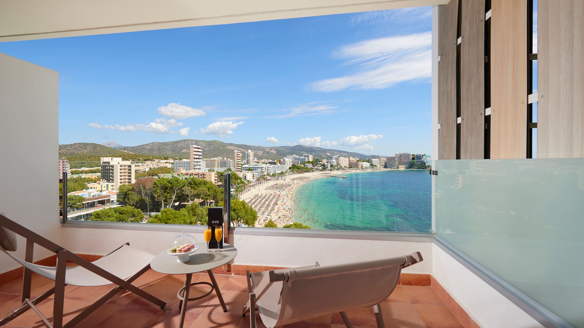a balcony with chairs and a table and a beach view