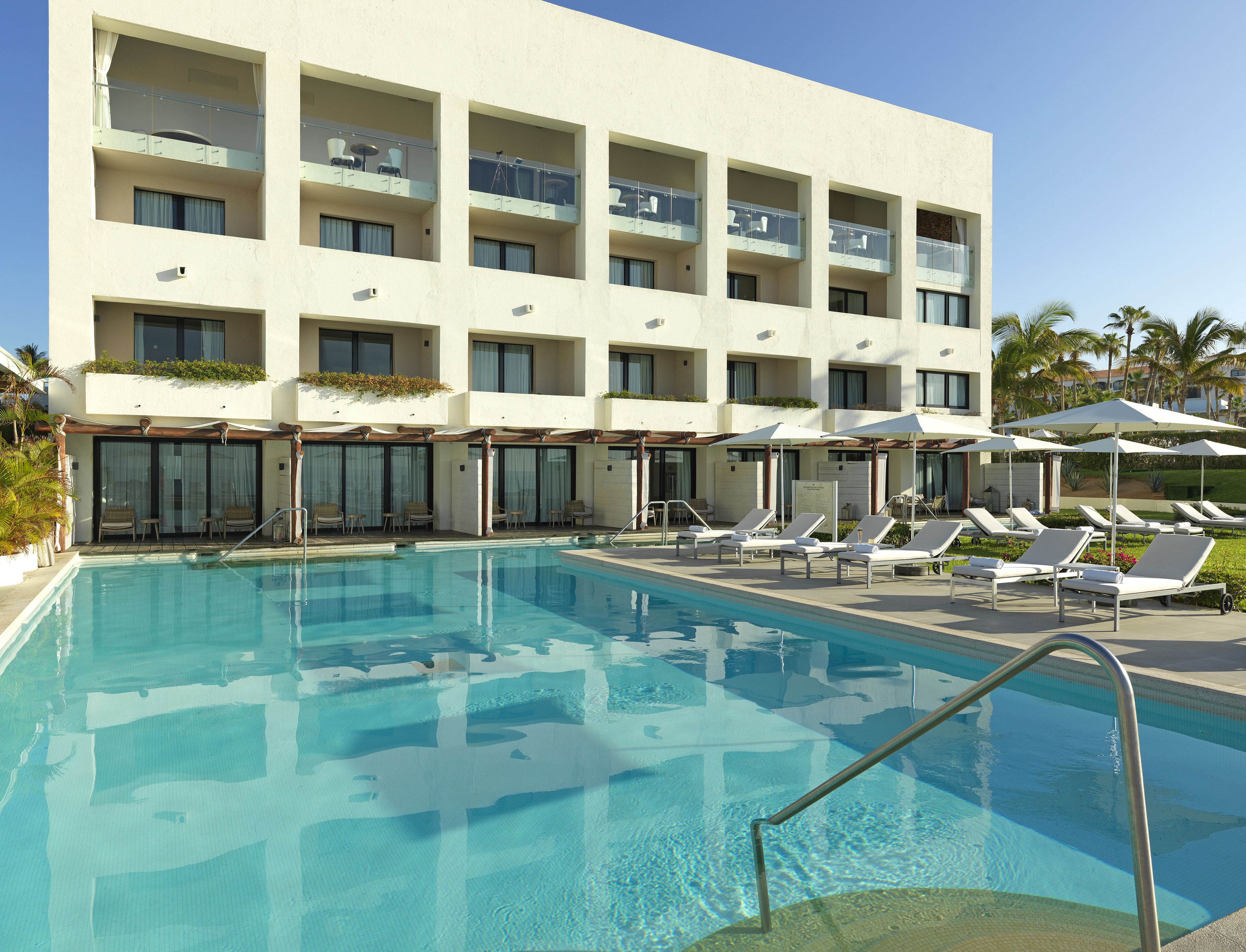 a pool with lounge chairs and a building