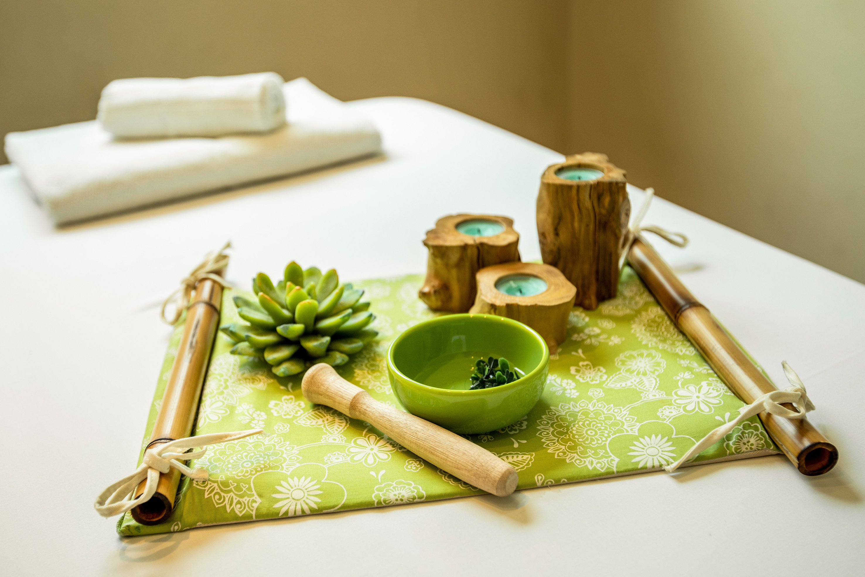 Natural spa decor: succulent, wooden candles, green bowl, and white towels.