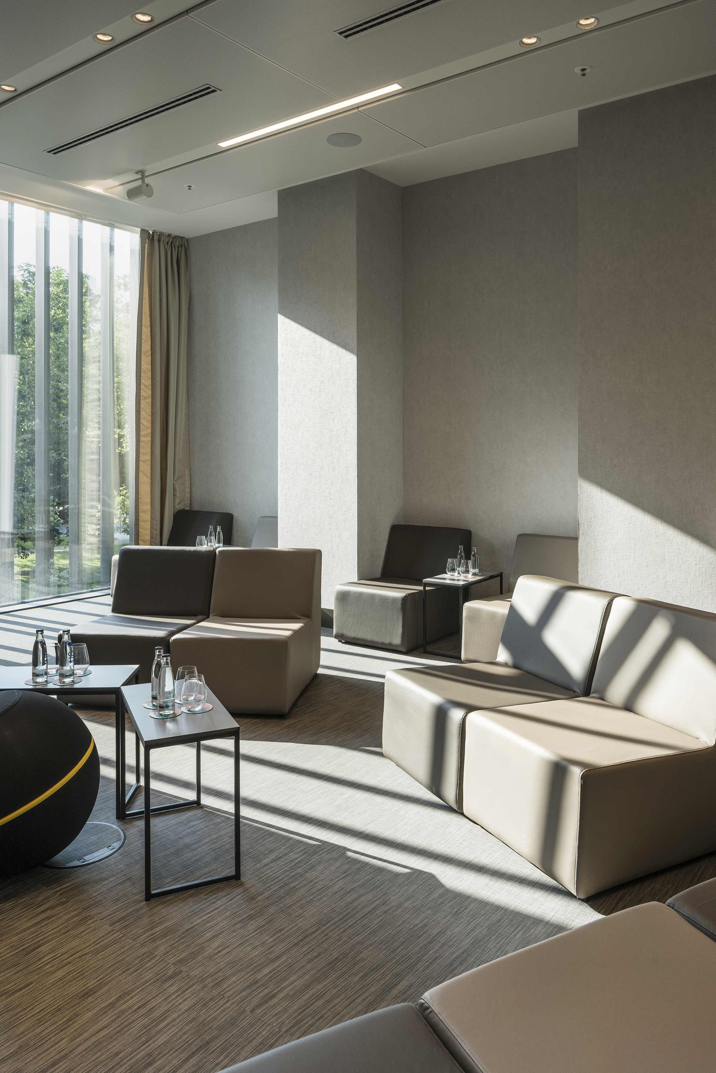Contemporary lounge with modular seating, glass tables, and natural window light.