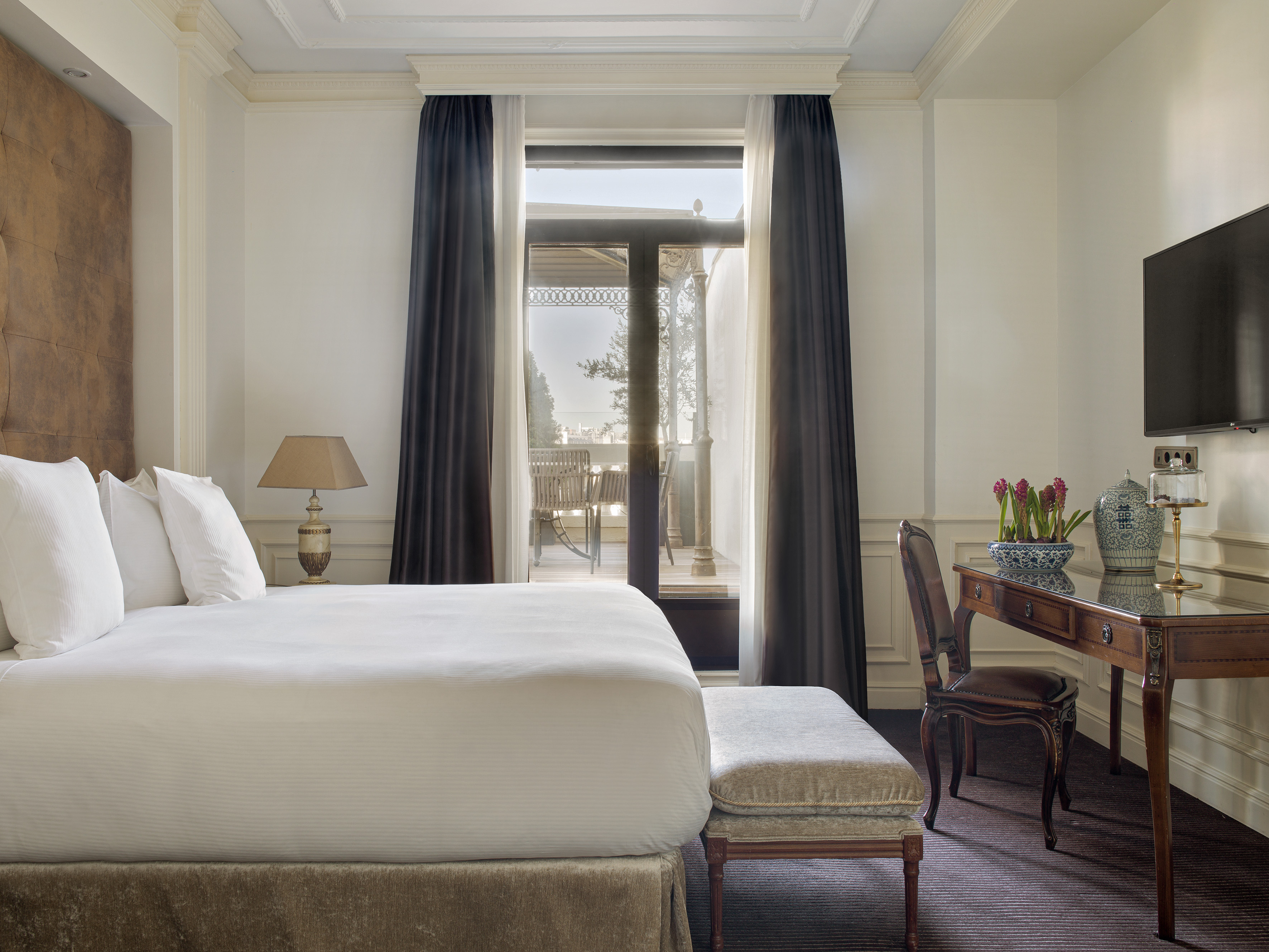 Luxury hotel room with comfortable bed, classic desk, and private balcony.