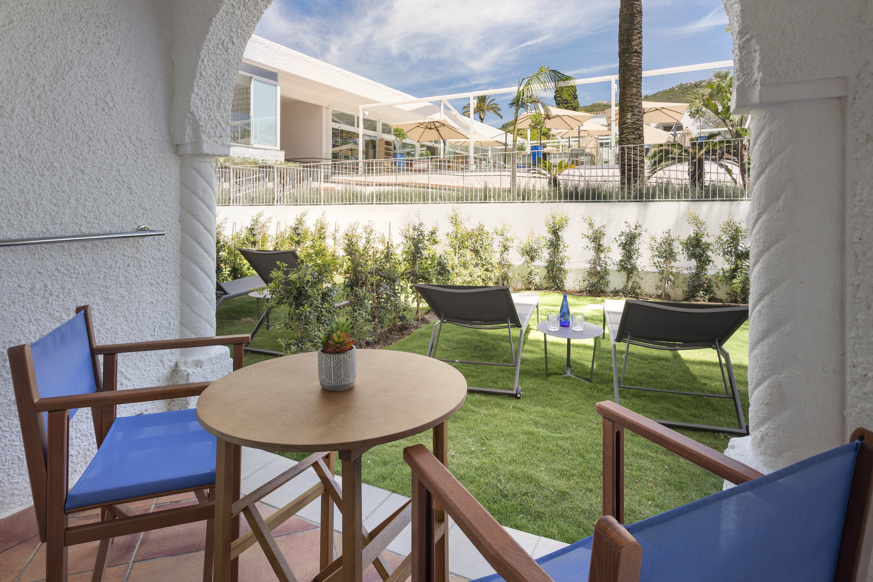 Arched hotel patio with outdoor seating, private garden, and resort lounge area.