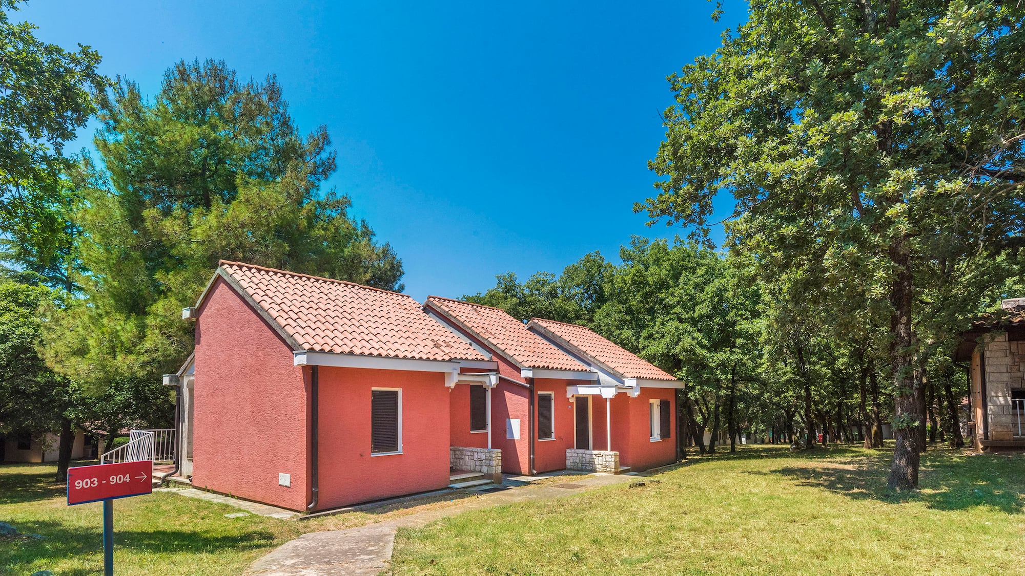 a two red houses with a lawn and trees in the background