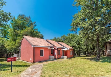 a two red houses with a lawn and trees in the background