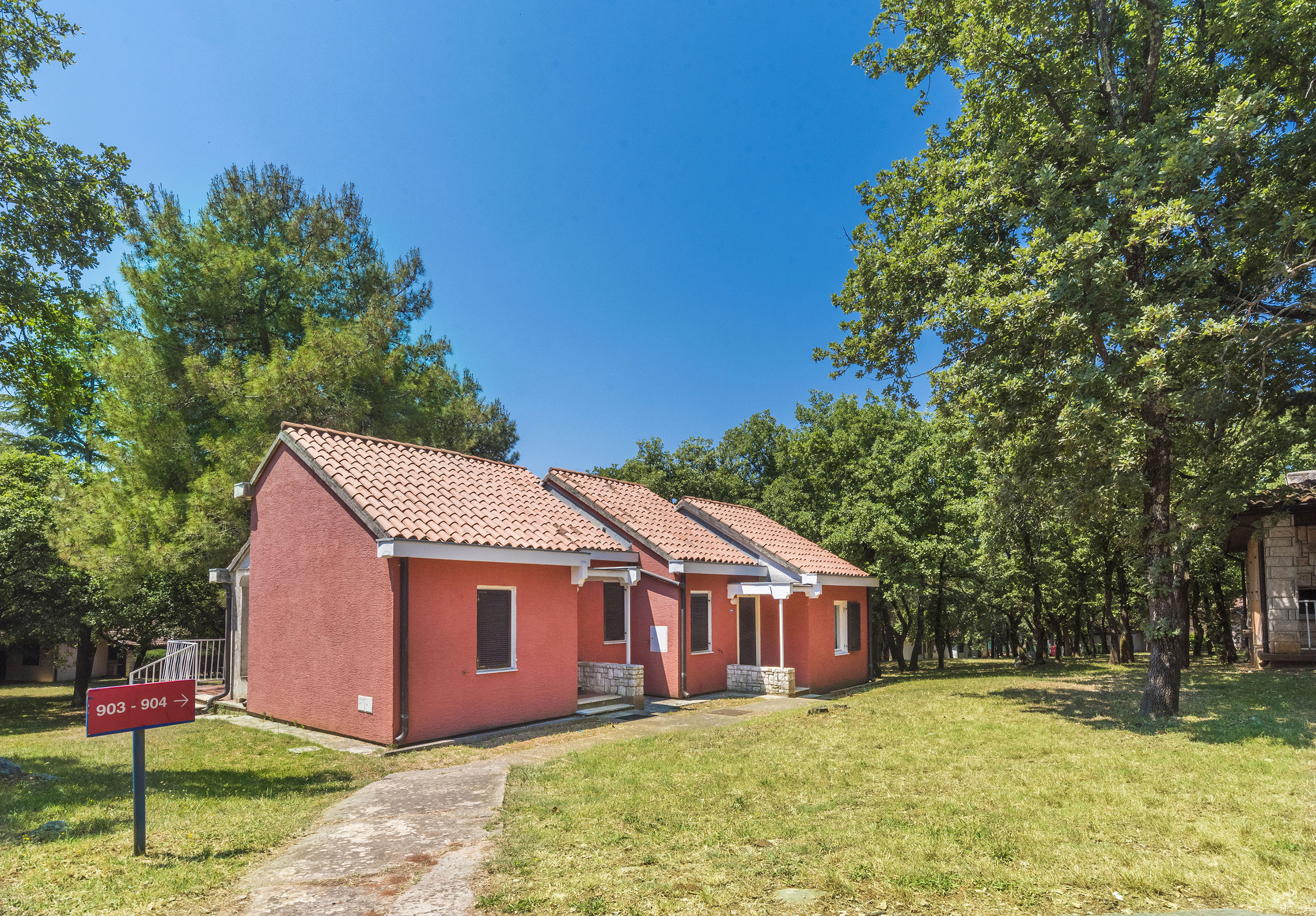 a two red houses with a lawn and trees in the background
