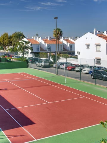 a tennis court with cars parked in front of it