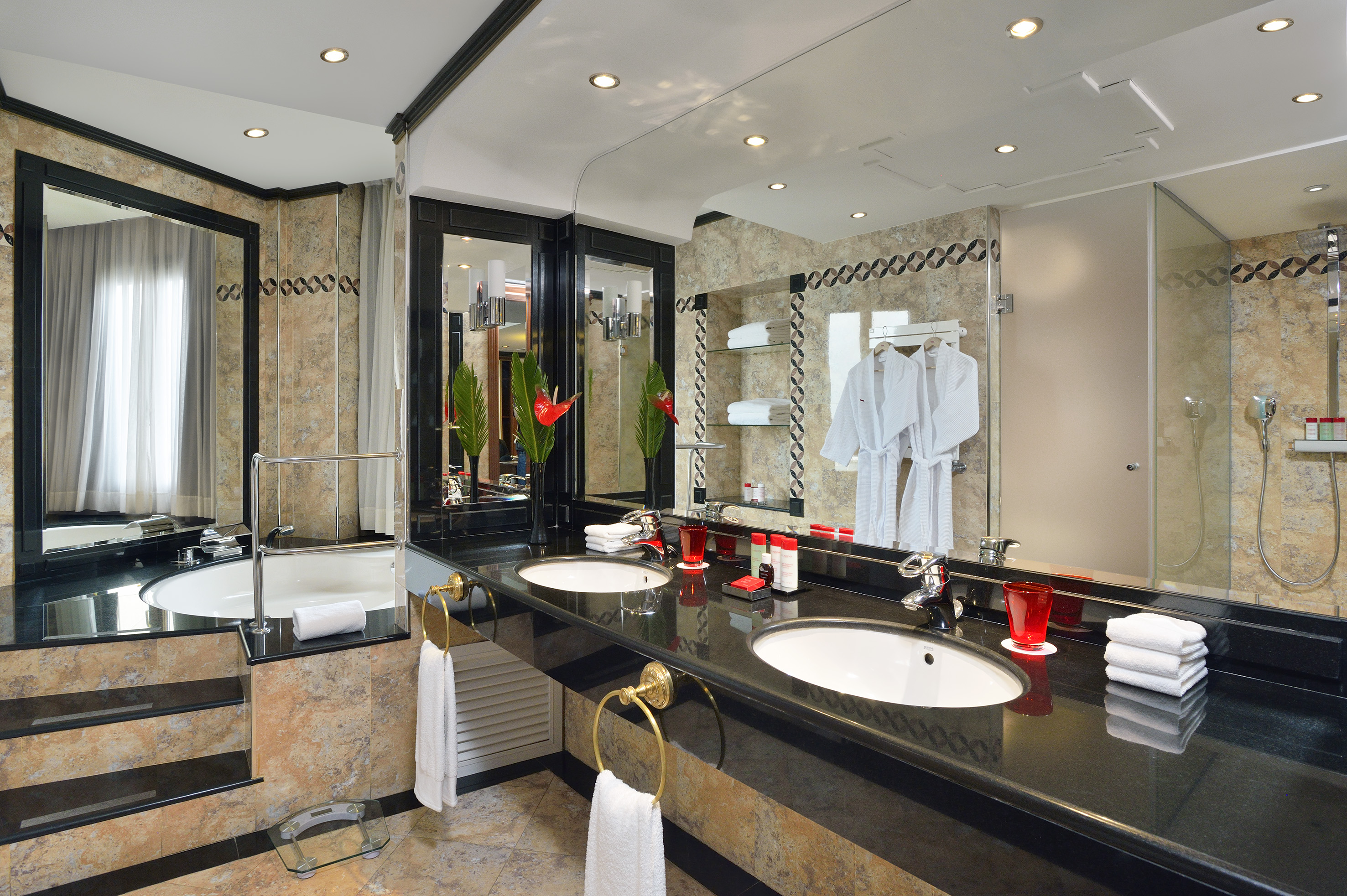 Luxury bathroom with double vanity, black counter, bathtub, and shower.