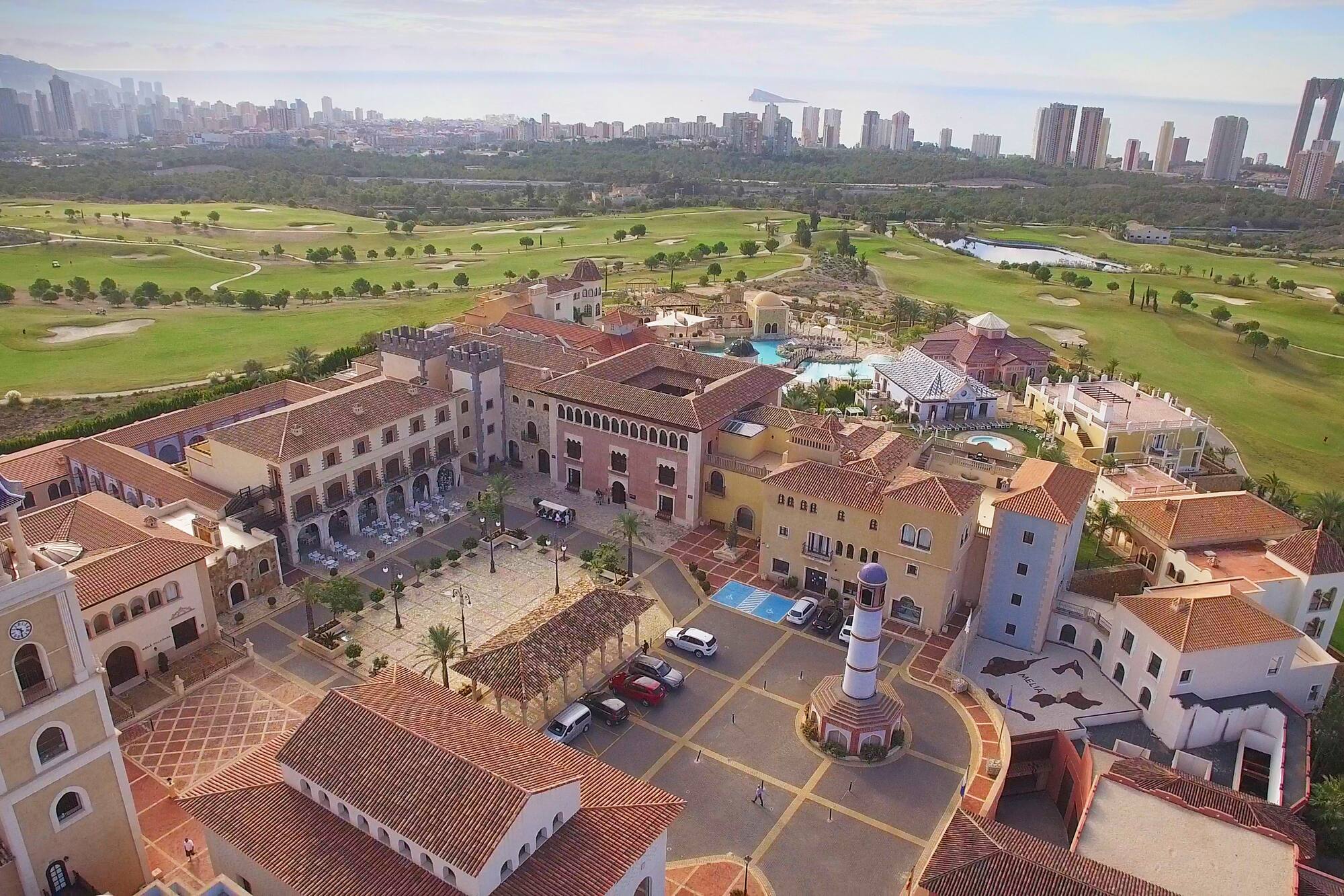 Spanish resort & golf course aerial, Benidorm cityscape backdrop.