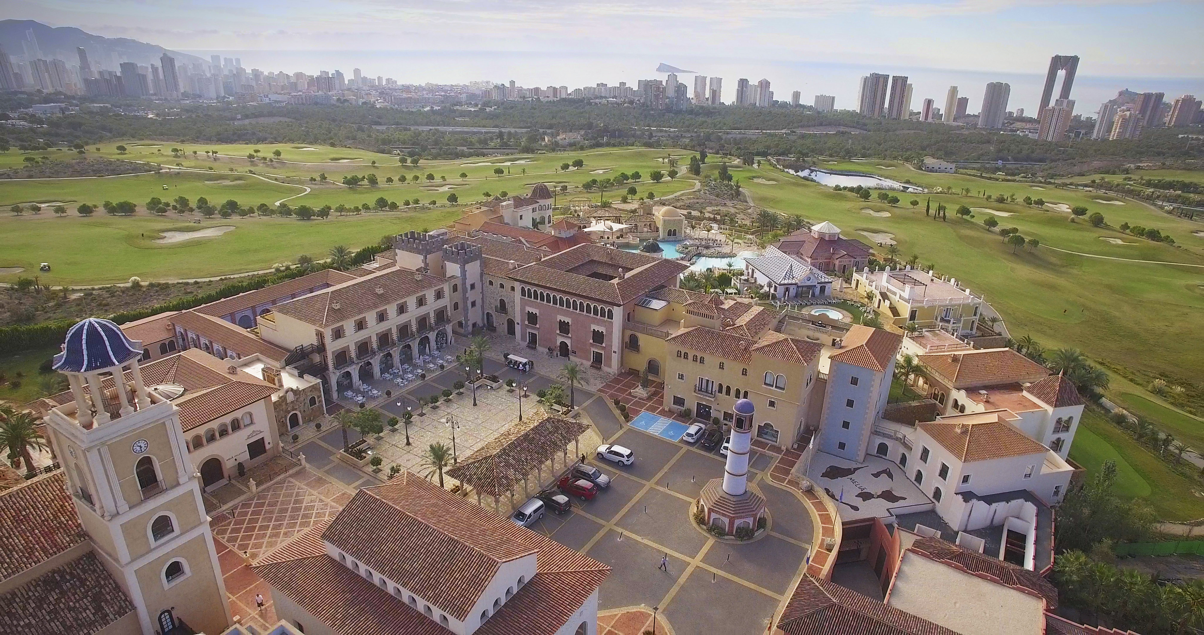 Spanish resort & golf course aerial, Benidorm cityscape backdrop.