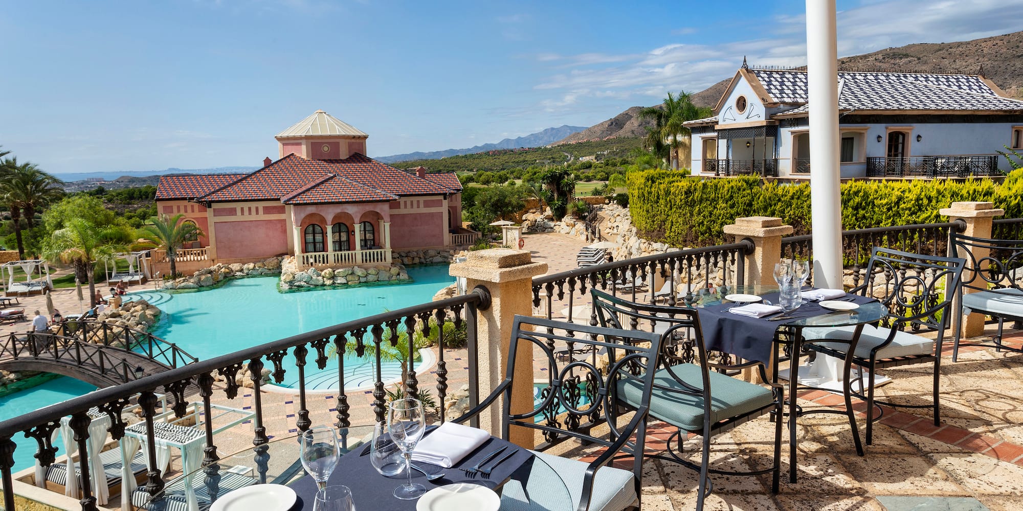 a table and chairs on a patio with a pool in the background