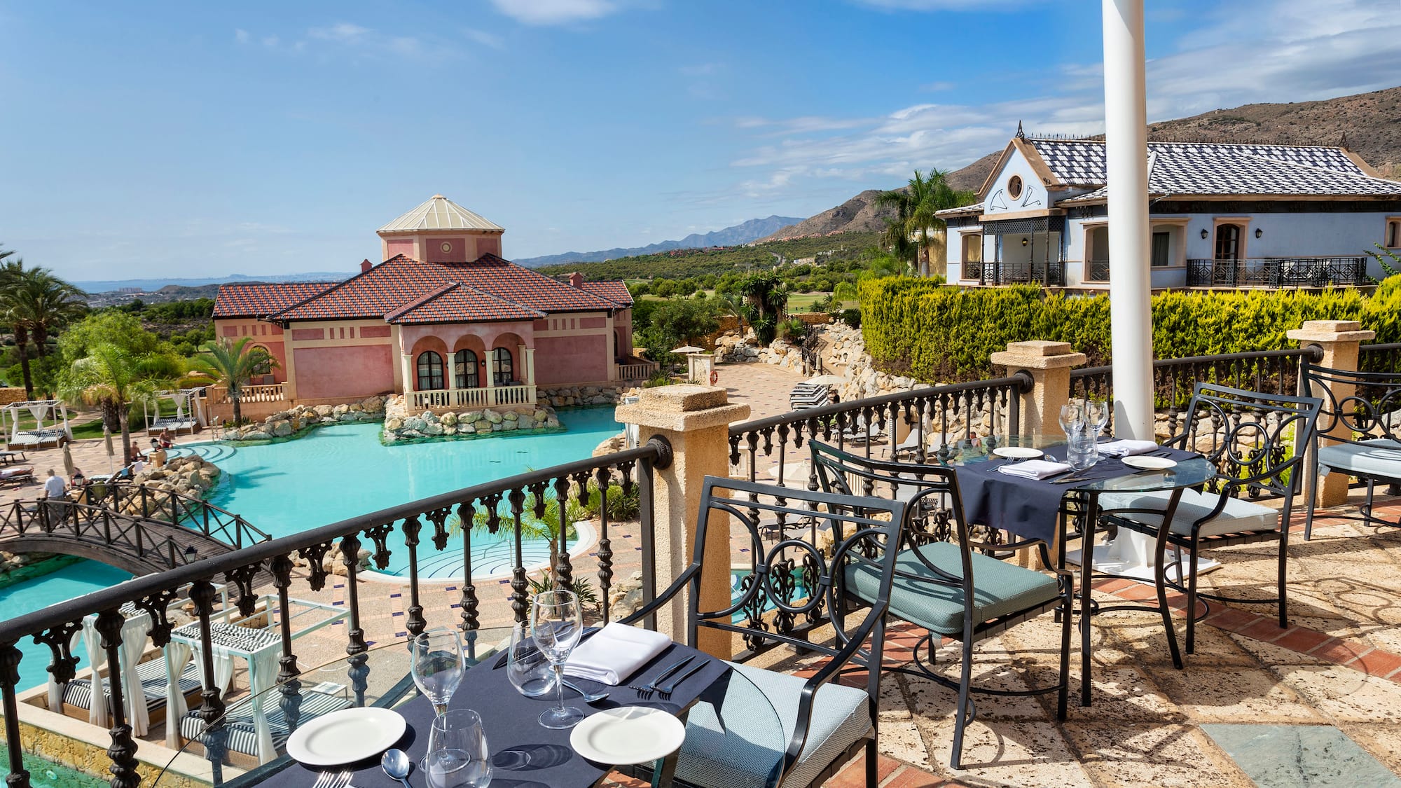 a table and chairs on a patio with a pool in the background