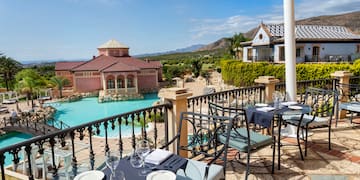 a table and chairs on a patio with a pool in the background