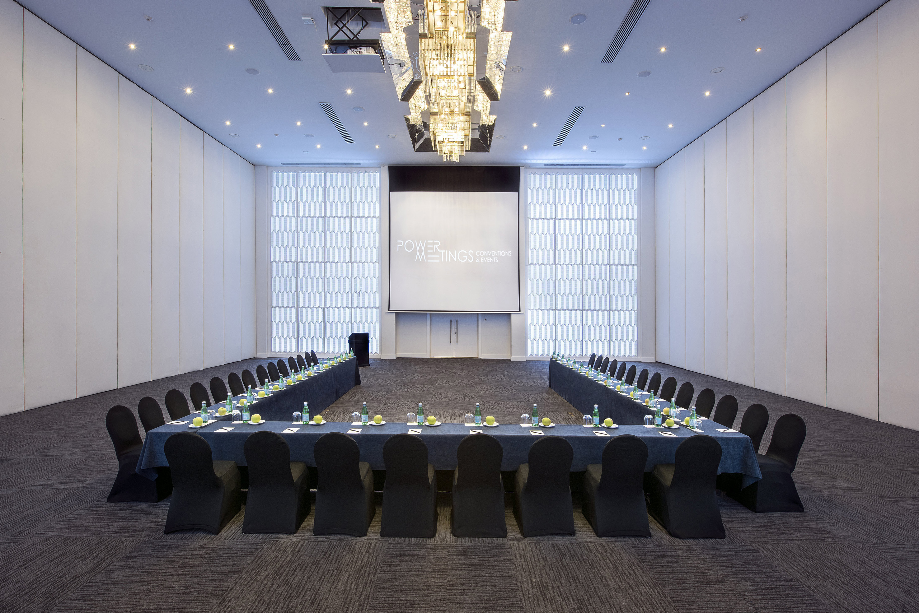 U-shape conference room with projection screen, setup for meetings and events.