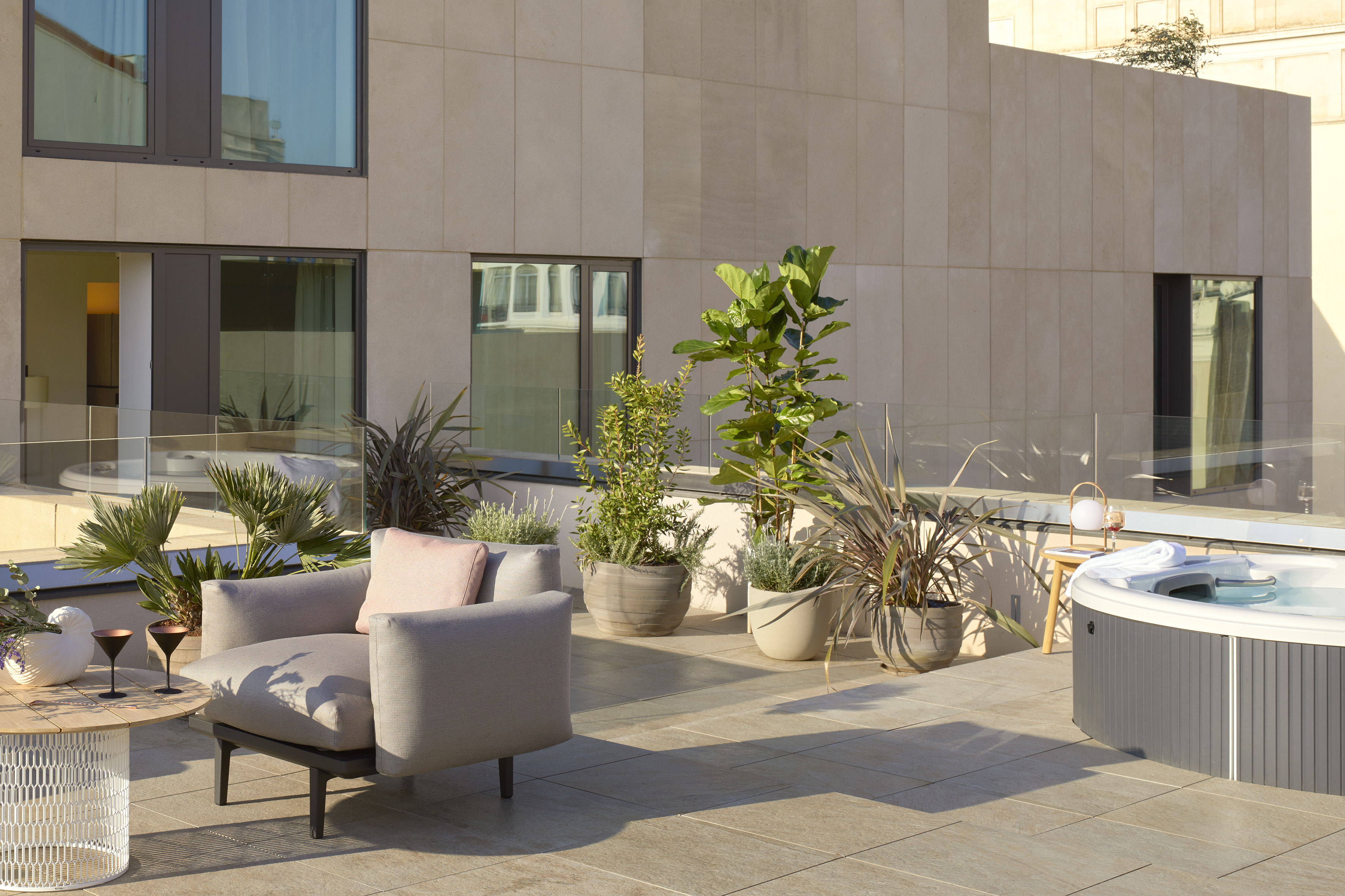 Modern rooftop terrace with hot tub, outdoor seating, and lush potted plants.