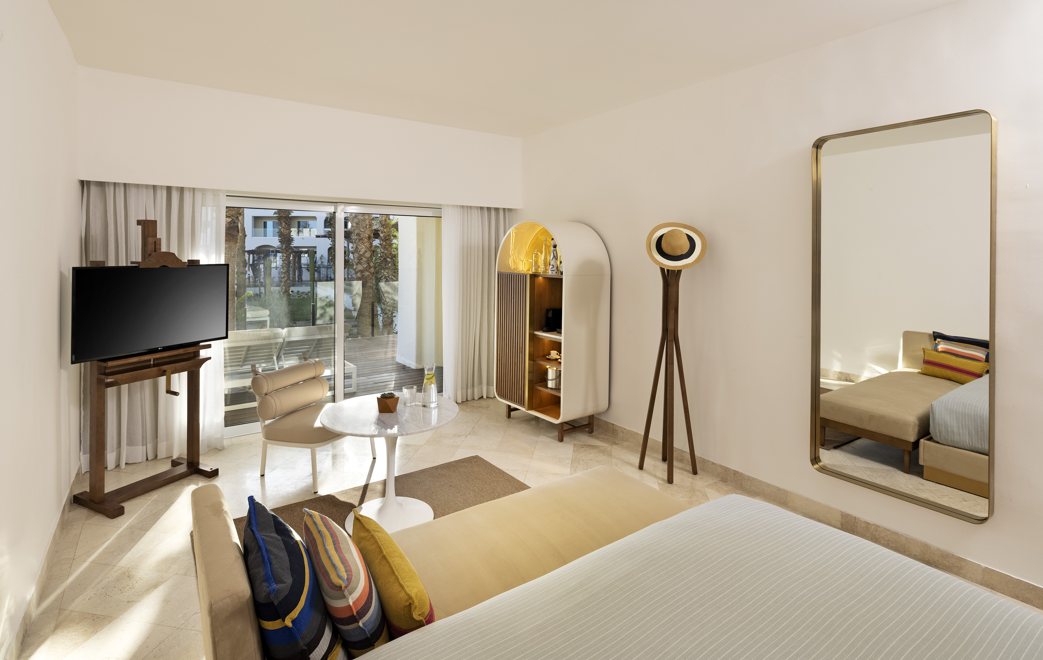 Modern hotel suite with balcony, TV, cabinet, and seating area.