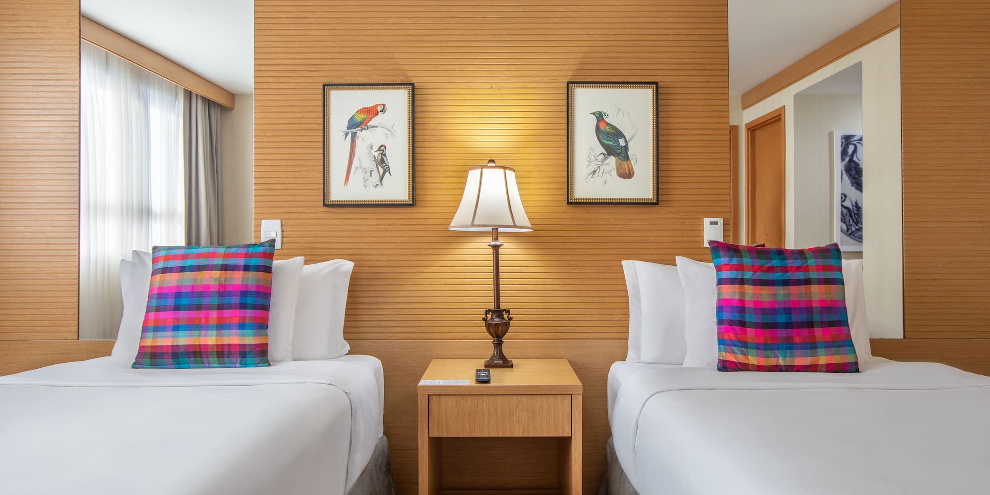 two beds with pillows and a lamp in a room