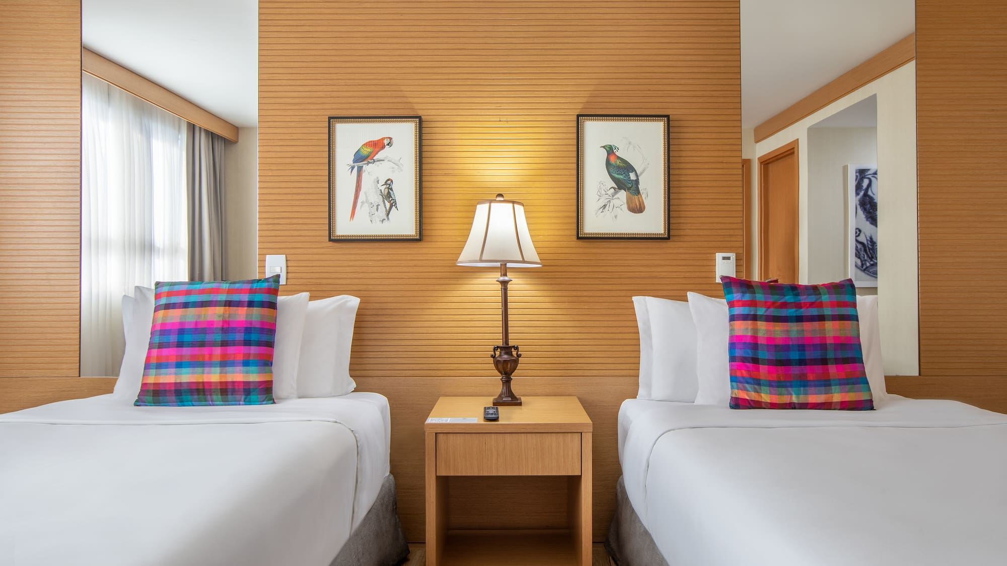 two beds with pillows and a lamp in a room