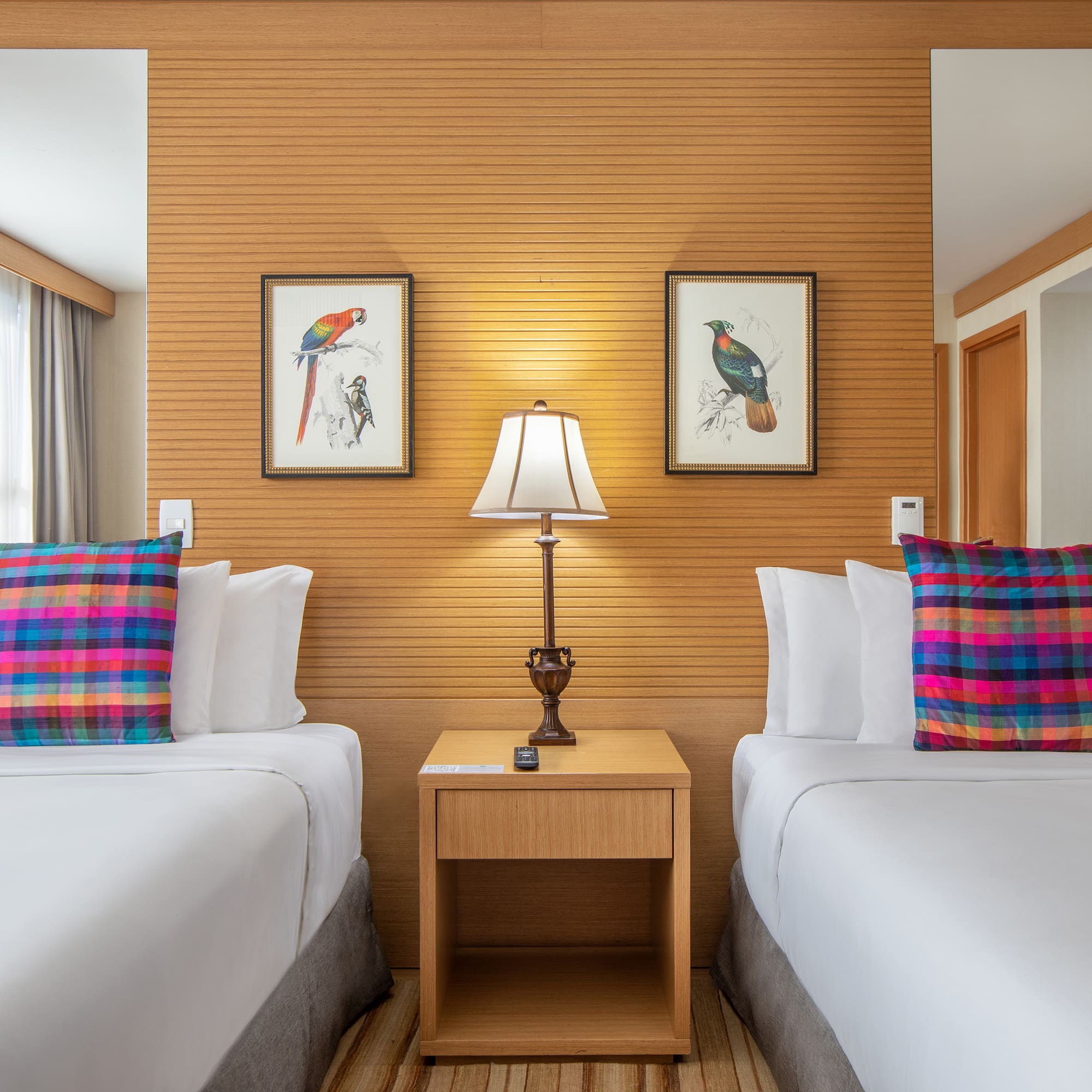 two beds with pillows and a lamp in a room