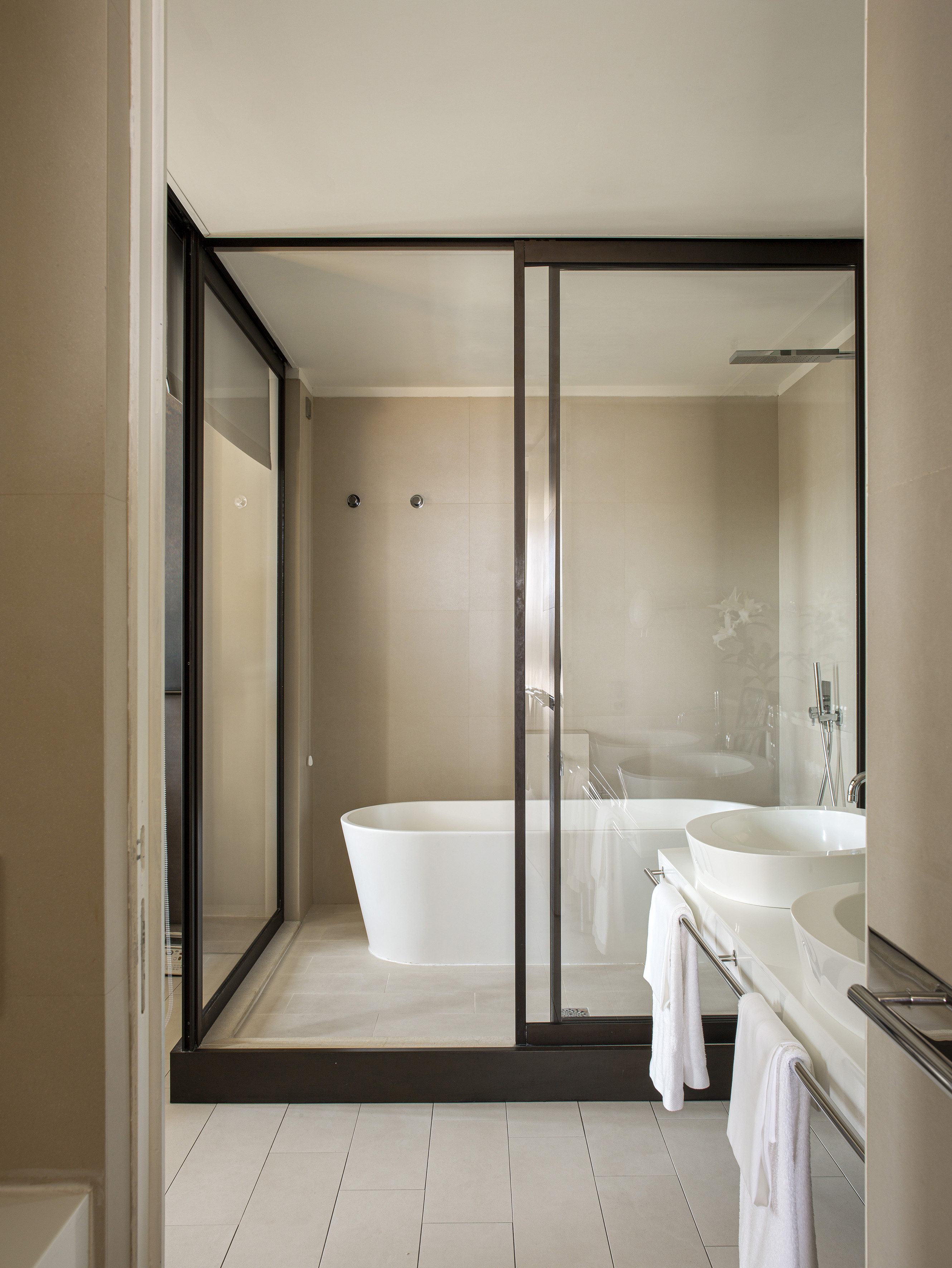 Modern bathroom: glass shower enclosure, freestanding tub, double vanity sinks.