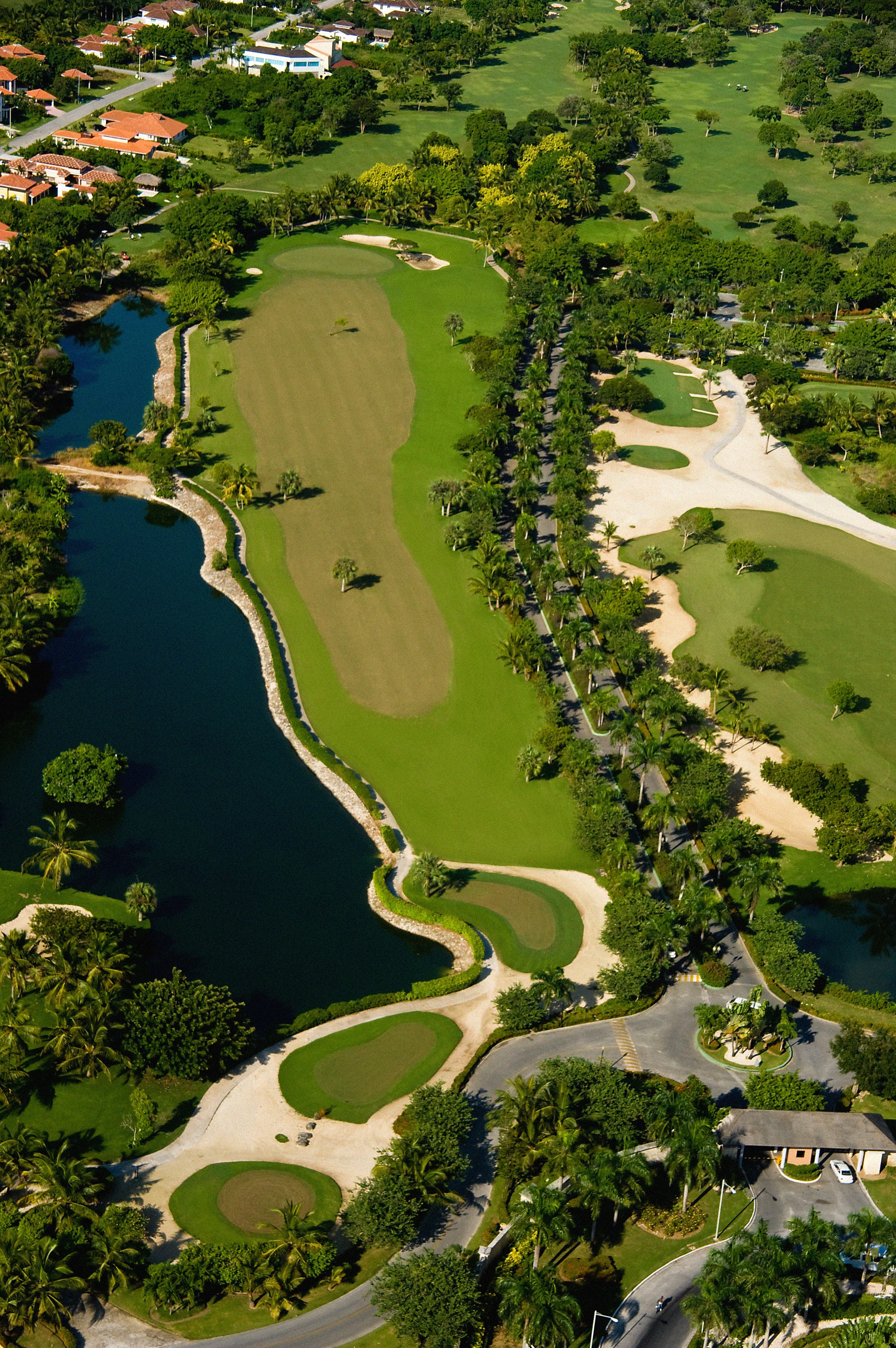 Tropical golf course aerial view with green fairways, water features, and palm trees.