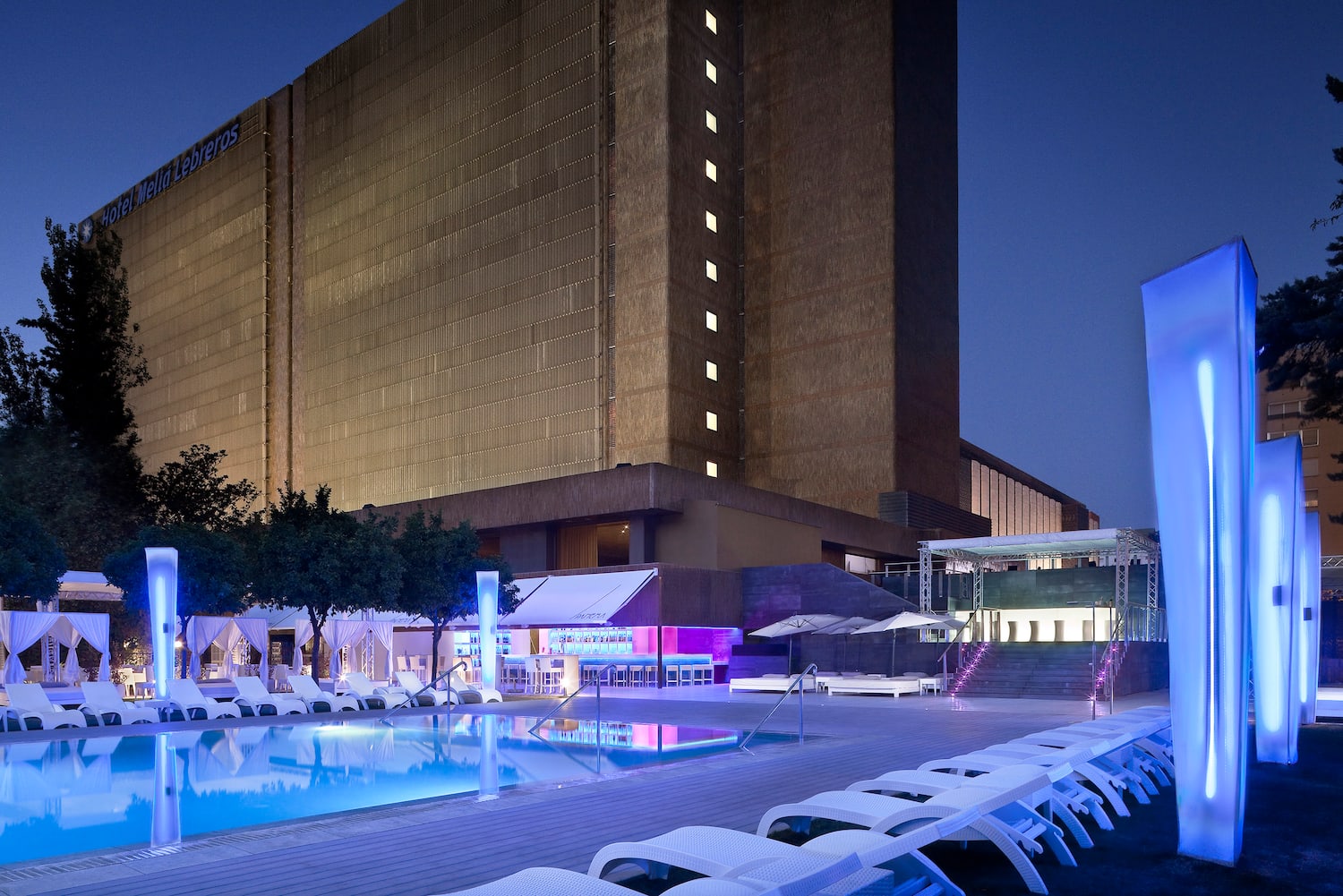 a pool and lounge chairs in front of a building