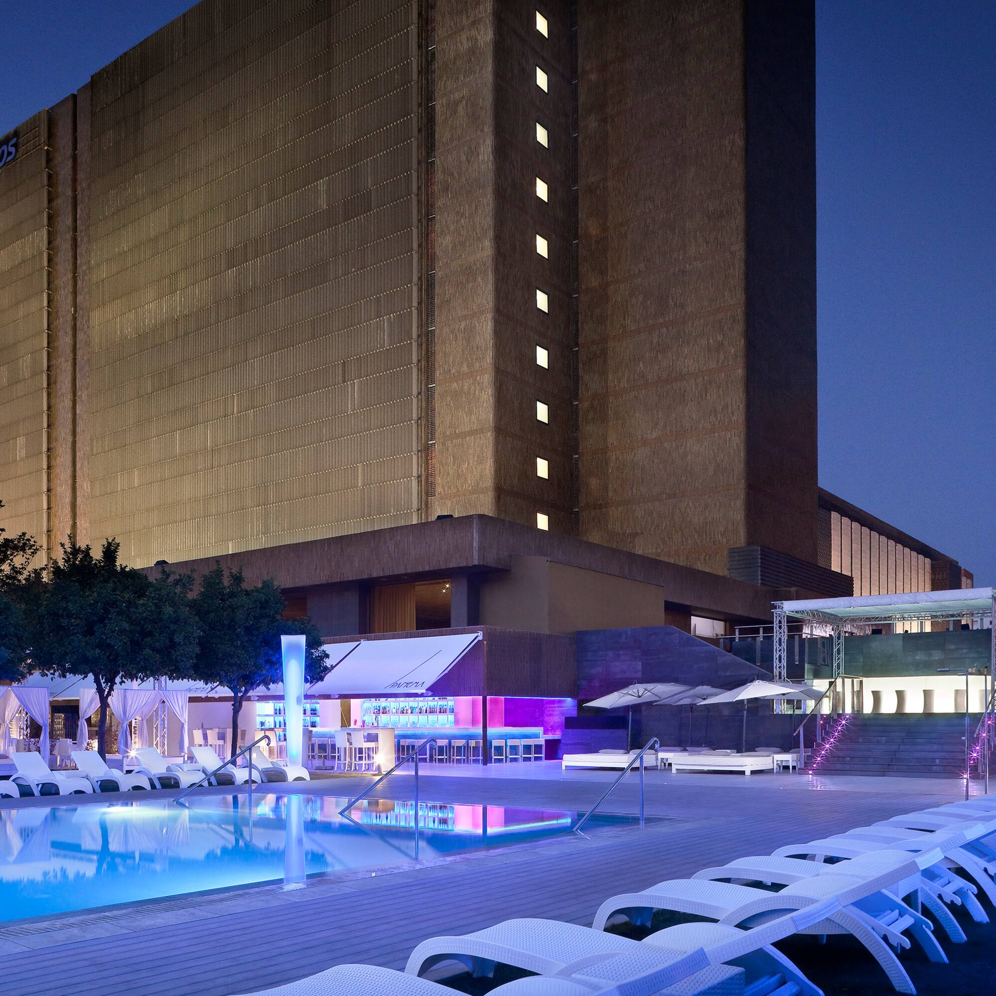 a pool and lounge chairs in front of a building