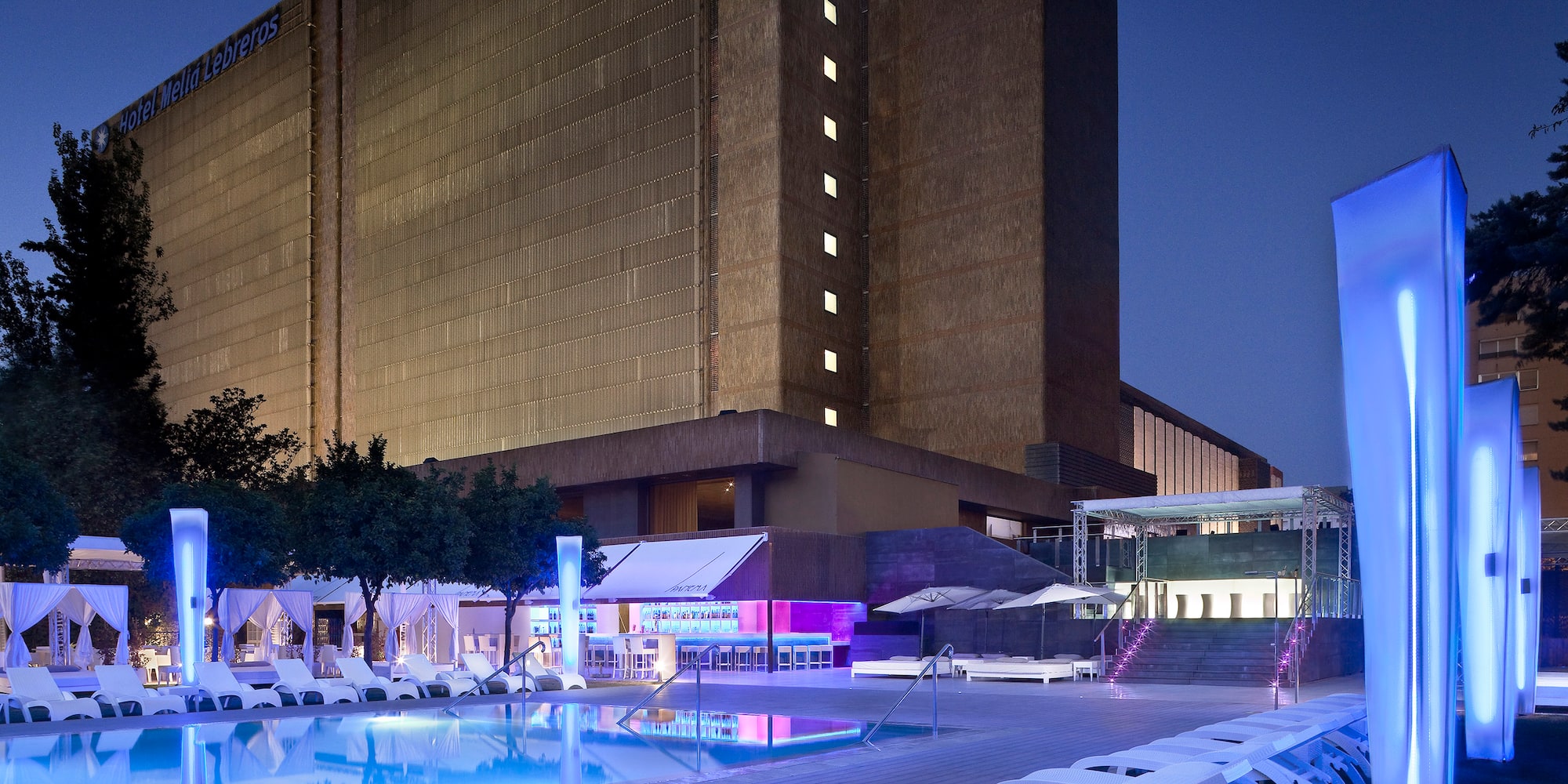 a pool and lounge chairs in front of a building